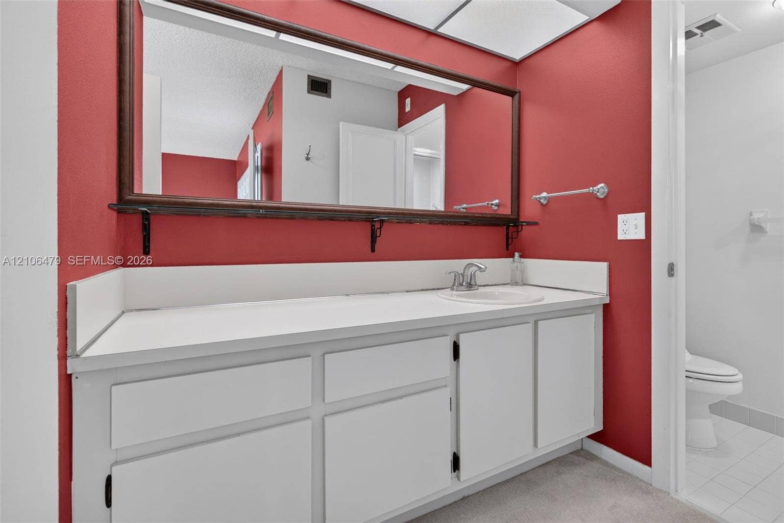 2800 SW 87th Avenue, #1113, Davie, FL 33328 Bathroom featuring a vanity with white cabinetry, a solid surface countertop with an integrated basin, a large wall-mounted mirror with a wood frame, and a separate water closet area