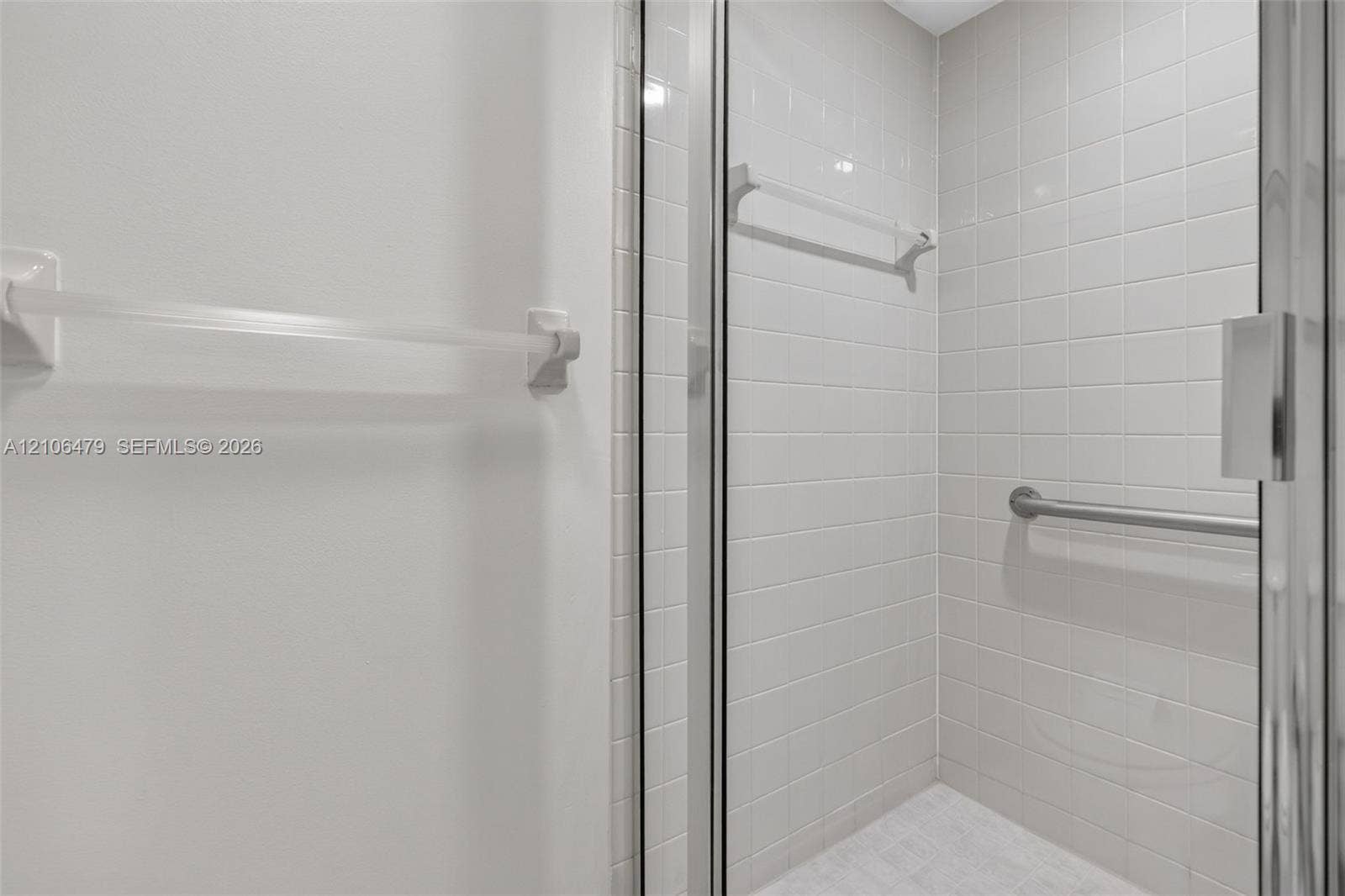 2800 SW 87th Avenue, #1113, Davie, FL 33328 Shower enclosure featuring white wall tiling, a glass door, a wall-mounted metal grab bar, and a horizontal towel rack