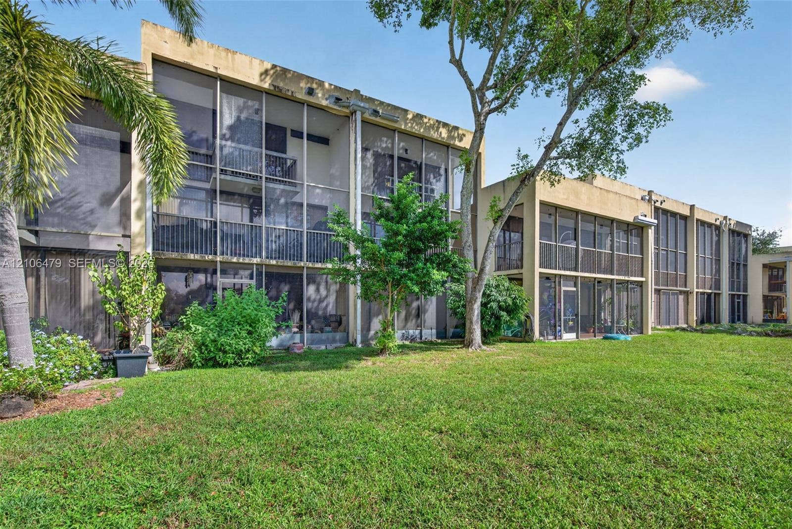 2800 SW 87th Avenue, #1113, Davie, FL 33328 Multi-level exterior featuring screened-in lanais, stucco facade, and established landscaping including mature palms and shade trees