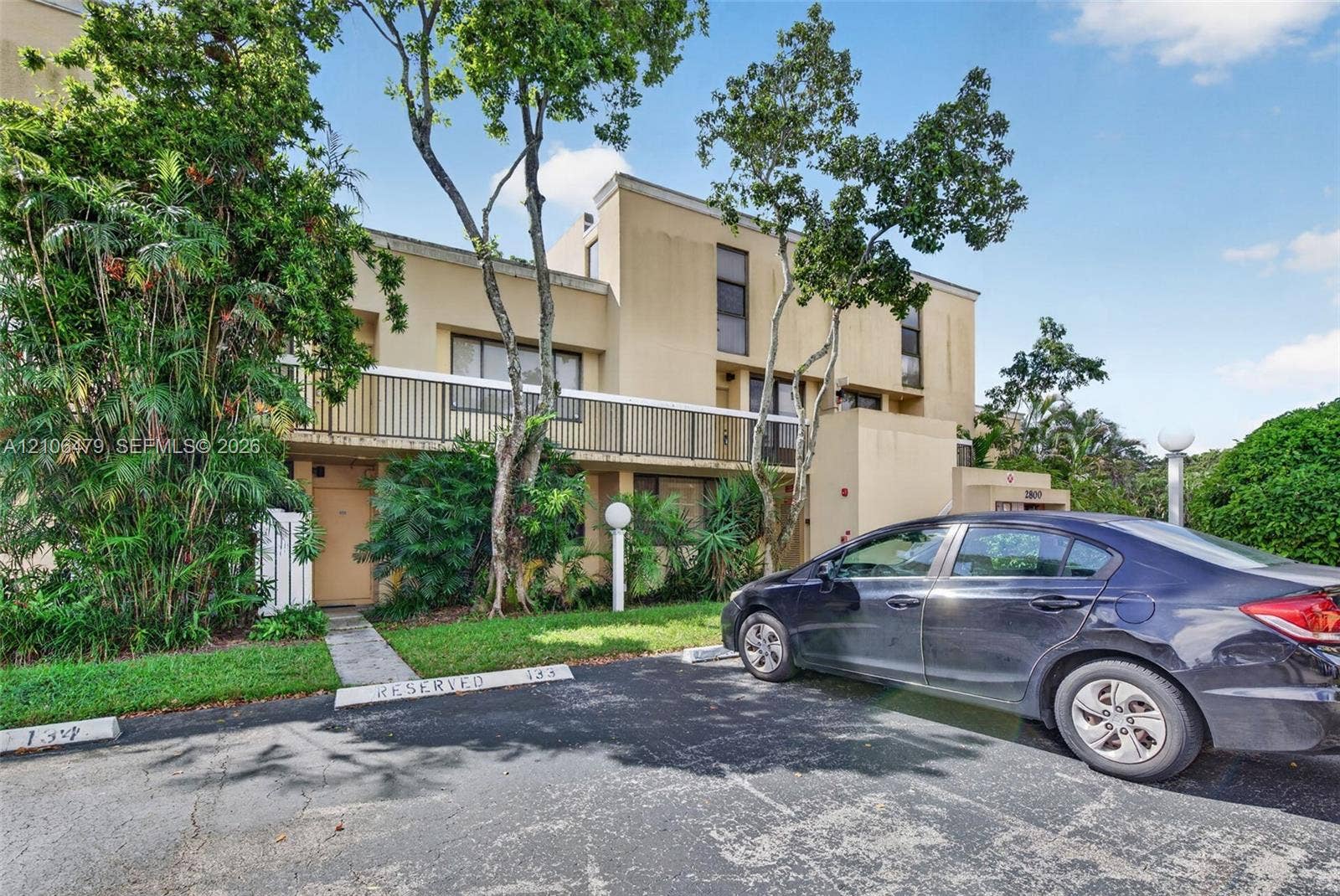 2800 SW 87th Avenue, #1113, Davie, FL 33328 Multi-story exterior featuring a stucco facade, balcony with metal railing, and dedicated parking spaces
