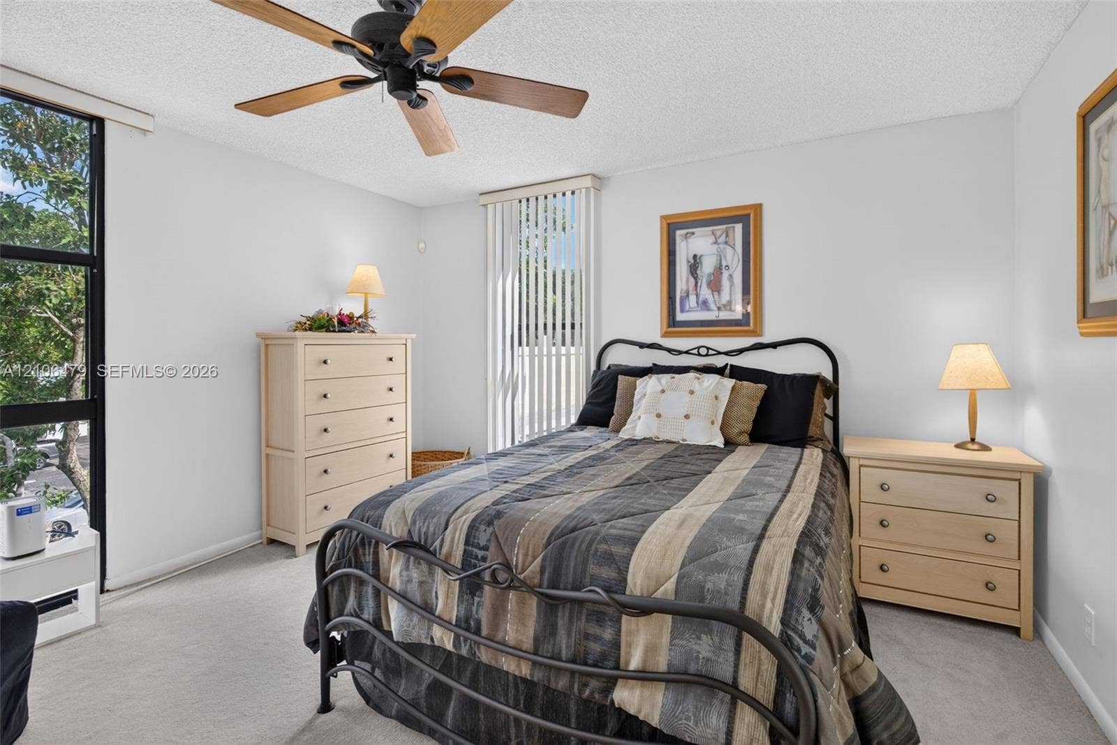 2800 SW 87th Avenue, #1113, Davie, FL 33328 Interior space featuring neutral carpeting, a black-finished ceiling fan with wood-toned blades, floor-to-ceiling black-framed windows, and vertical blinds