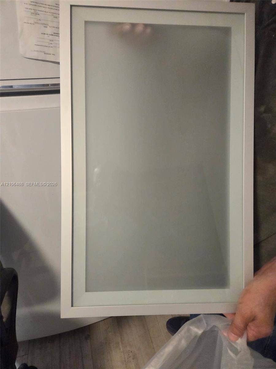 Rectangular cabinet door featuring a slim metallic frame with a centered frosted glass panel
