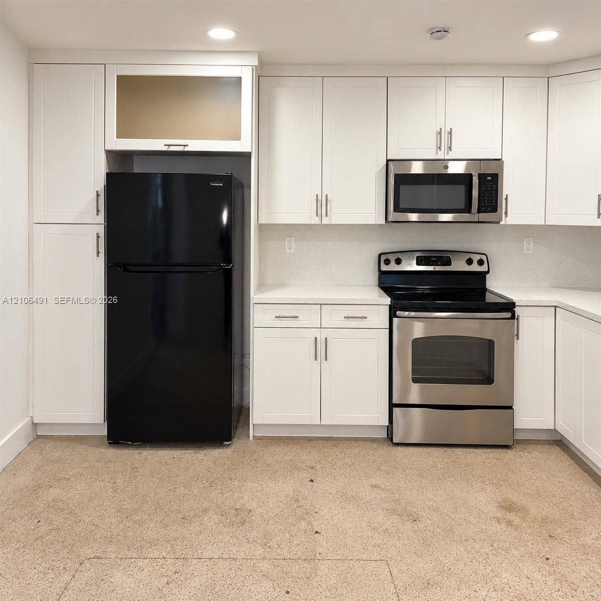 Kitchen featuring white cabinetry, solid surface countertops, a stainless steel range, a stainless steel microwave, and recessed lighting