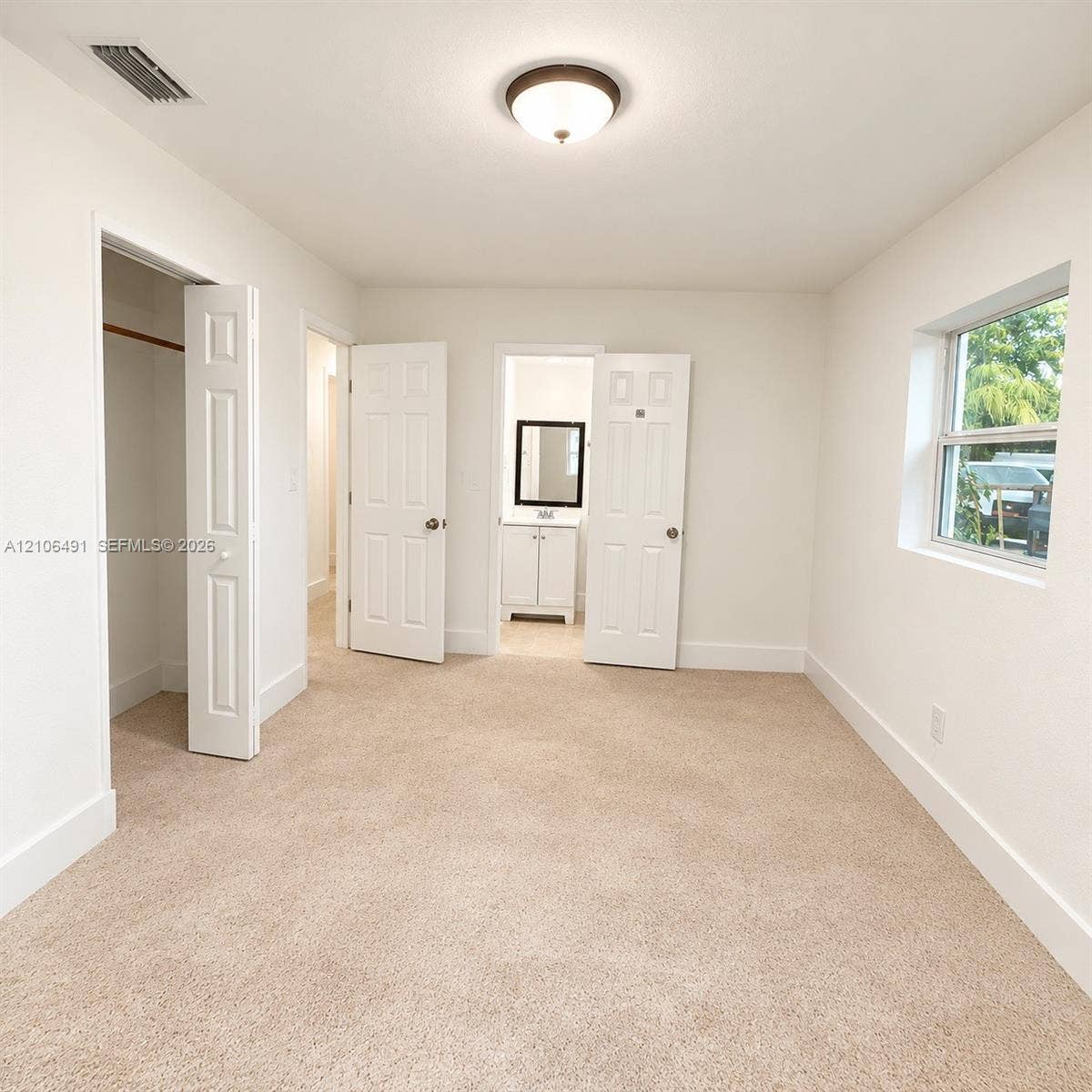 Neutral wall-to-wall carpeting, flush-mount ceiling lighting, multi-panel interior doors, and a closet with a built-in rod