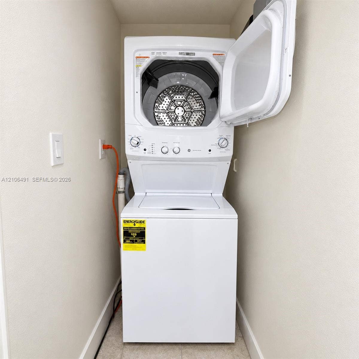 White stacked laundry unit featuring a top-loading washer and front-loading dryer with a metallic drum finish