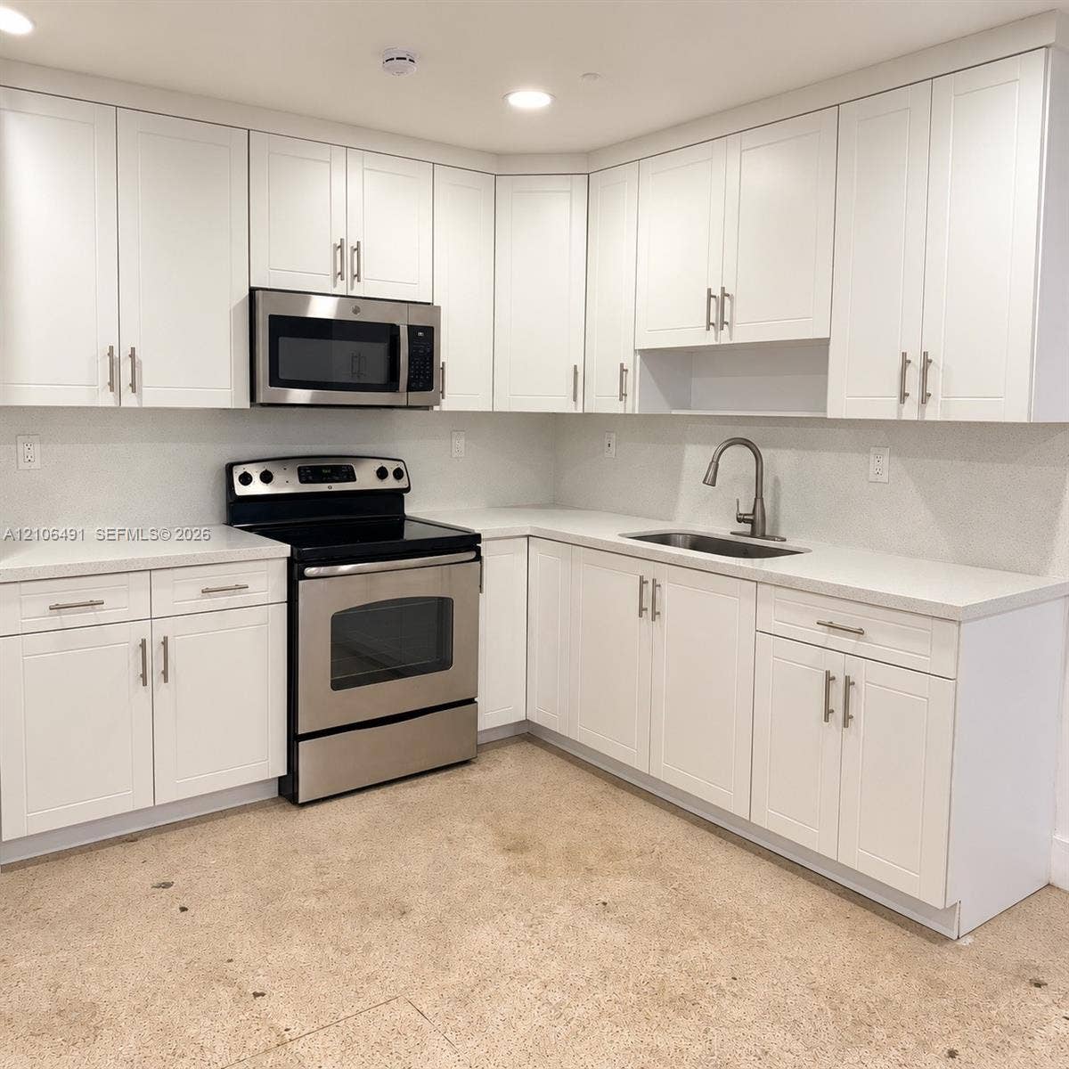 Kitchen featuring white shaker-style cabinetry, stainless steel appliances, solid surface countertops, and an undermount sink with a gooseneck faucet