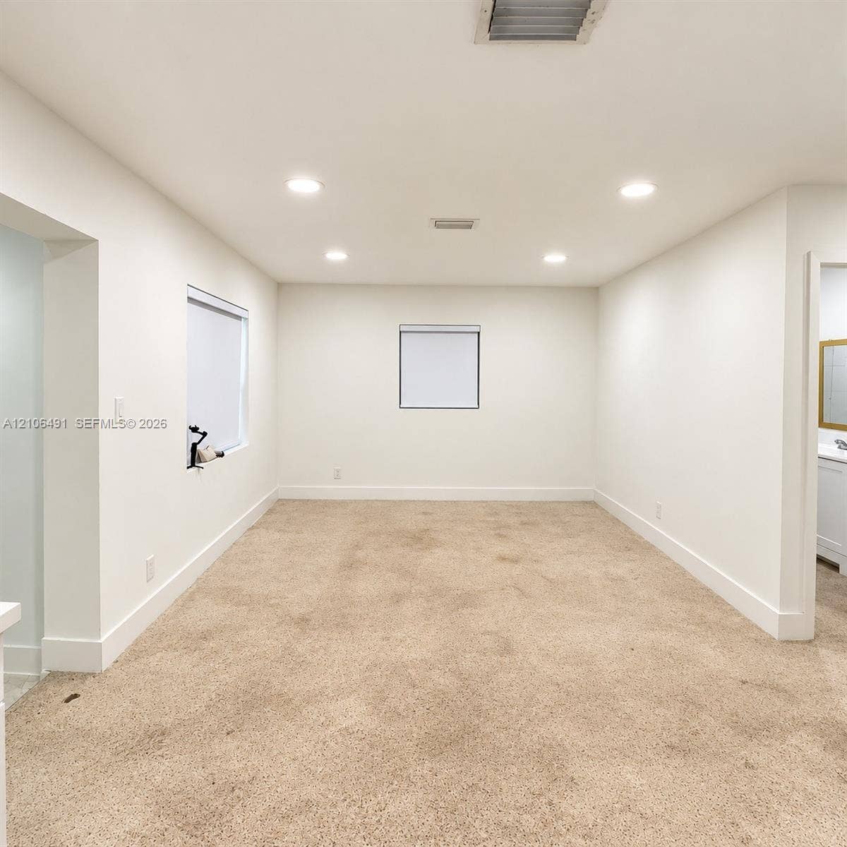 Neutral-toned carpeting, recessed ceiling lighting, and multiple windows