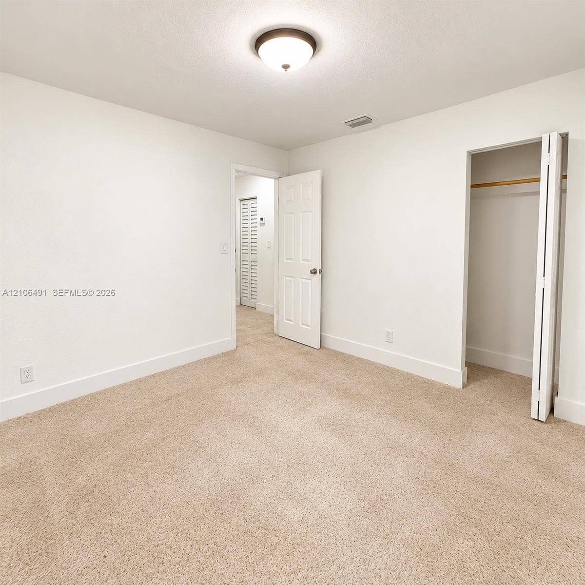 Neutral-toned carpeted flooring, flush-mount ceiling lighting, and a closet with bifold doors