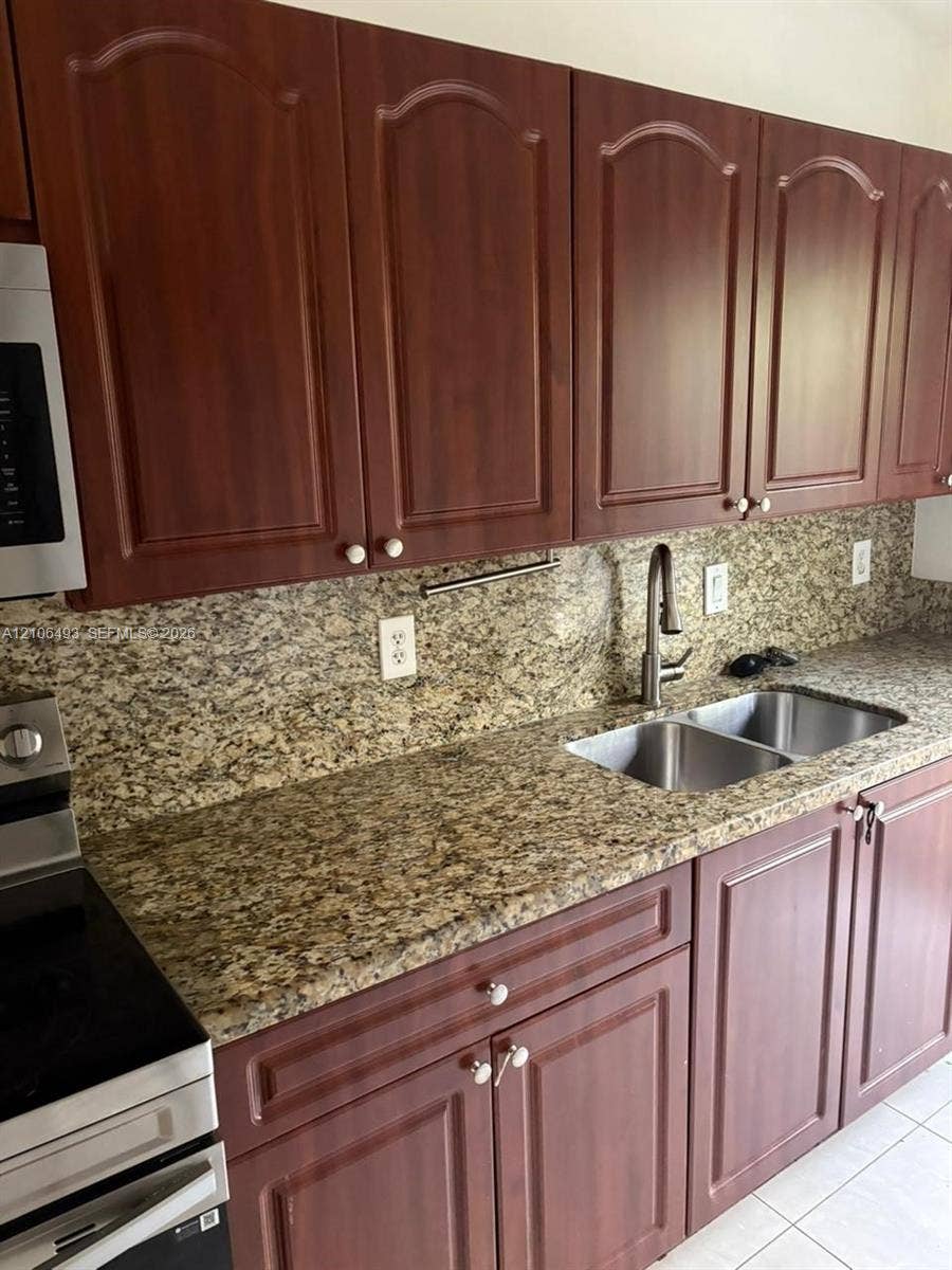 117 SE 3rd Avenue, #7, Hallandale Beach, FL 33009 Raised-panel cabinetry, stone-surface countertops, stone-surface backsplash, stainless steel double-basin sink, and high-arc pull-down faucet