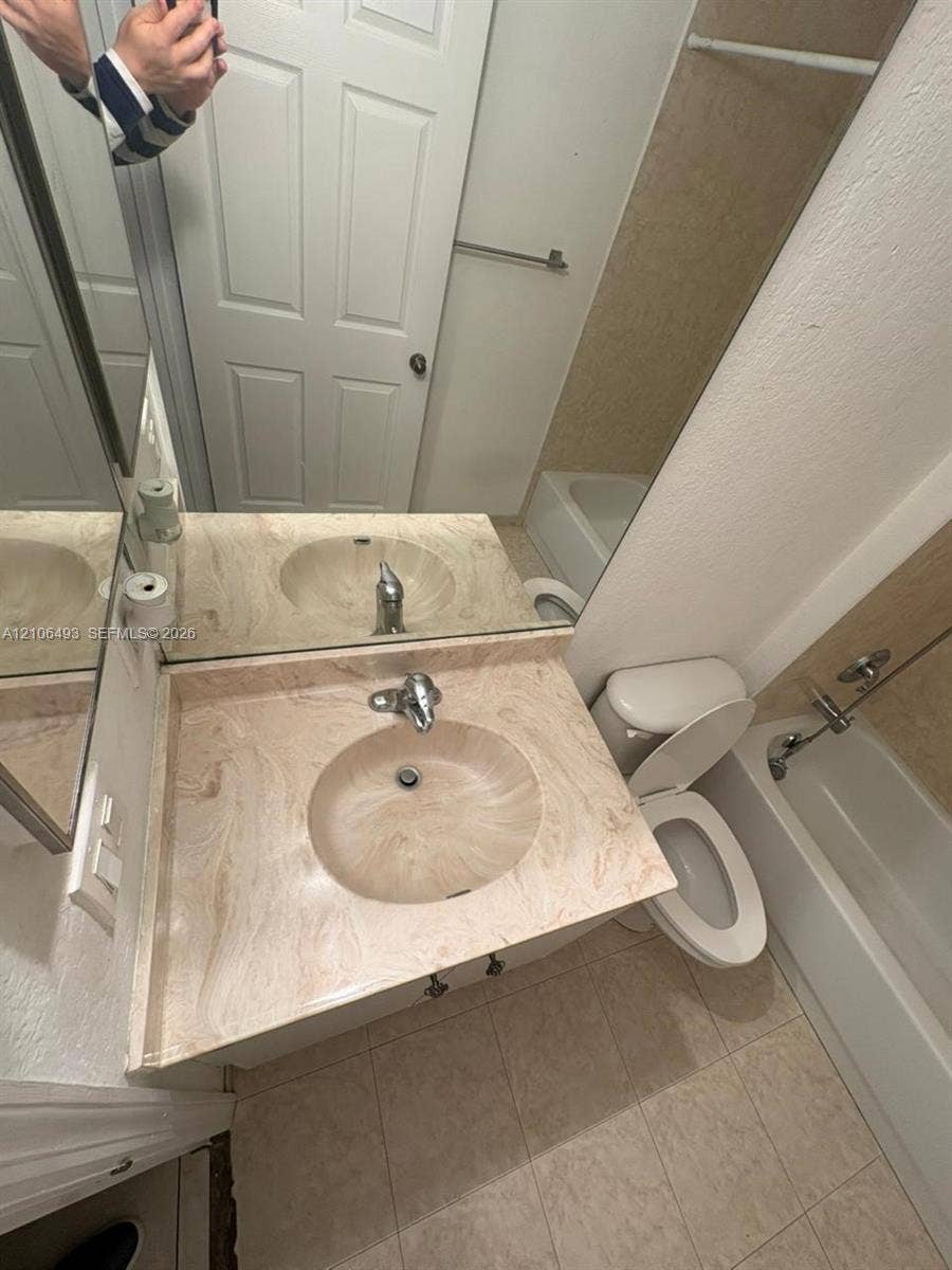 117 SE 3rd Avenue, #7, Hallandale Beach, FL 33009 Bathroom featuring a vanity with an integrated basin, a large wall-mounted mirror, ceramic tile flooring, and a shower-tub combination with a tiled surround