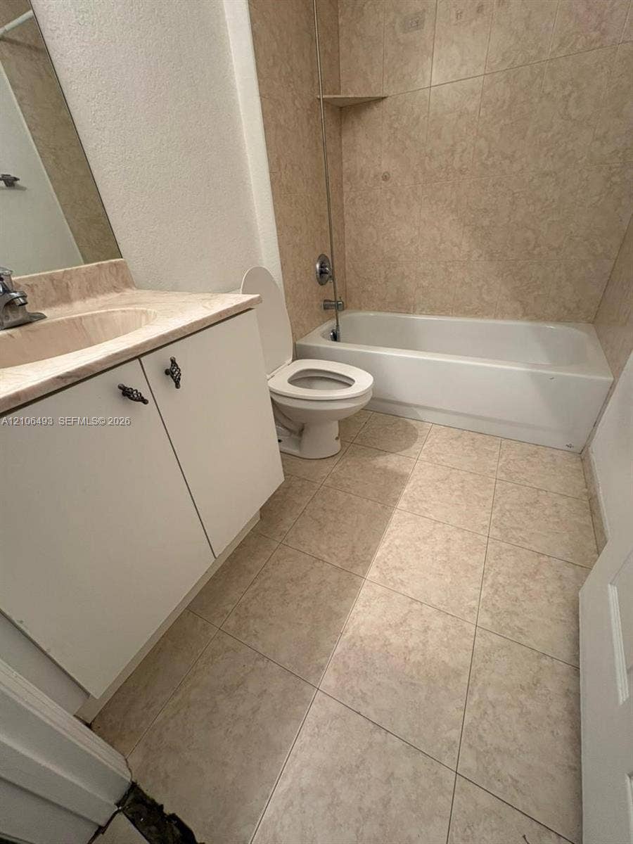 117 SE 3rd Avenue, #7, Hallandale Beach, FL 33009 Bathroom featuring tile flooring, a vanity with a stone-top surface, an integrated sink basin, and a tub-shower combination with tiled surround