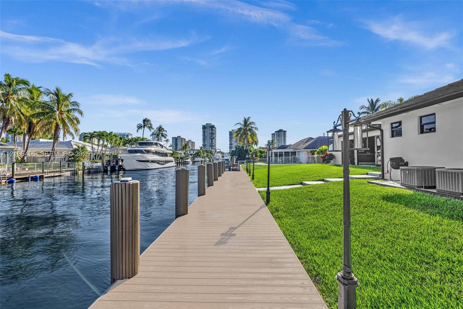 Waterfront property featuring a private bulkhead dock, manicured lawn, stone paver pathway, and nautical piling hardware