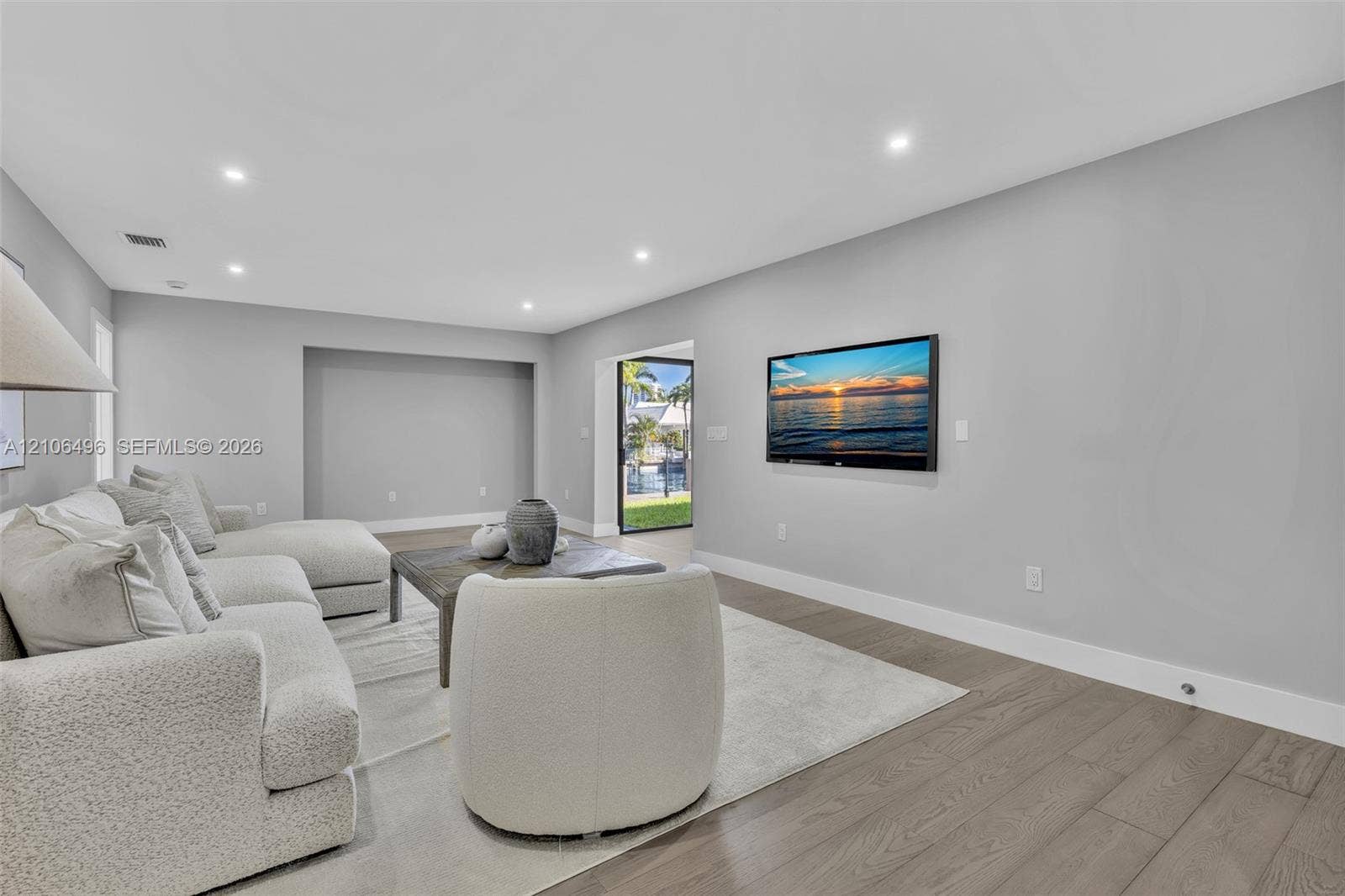 Living area featuring recessed lighting, neutral wall paint, wood-finish flooring, and a recessed wall niche