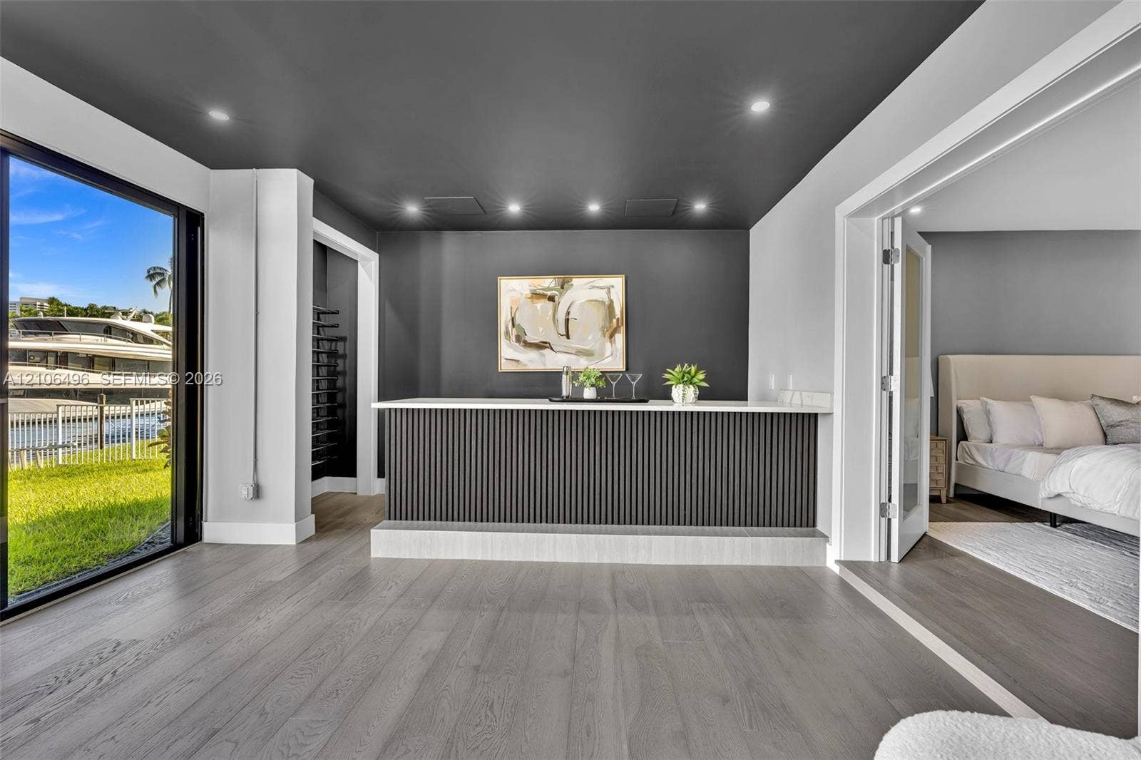 Built-in wet bar featuring a fluted front, stone countertop, recessed lighting, and a dark-toned accent wall