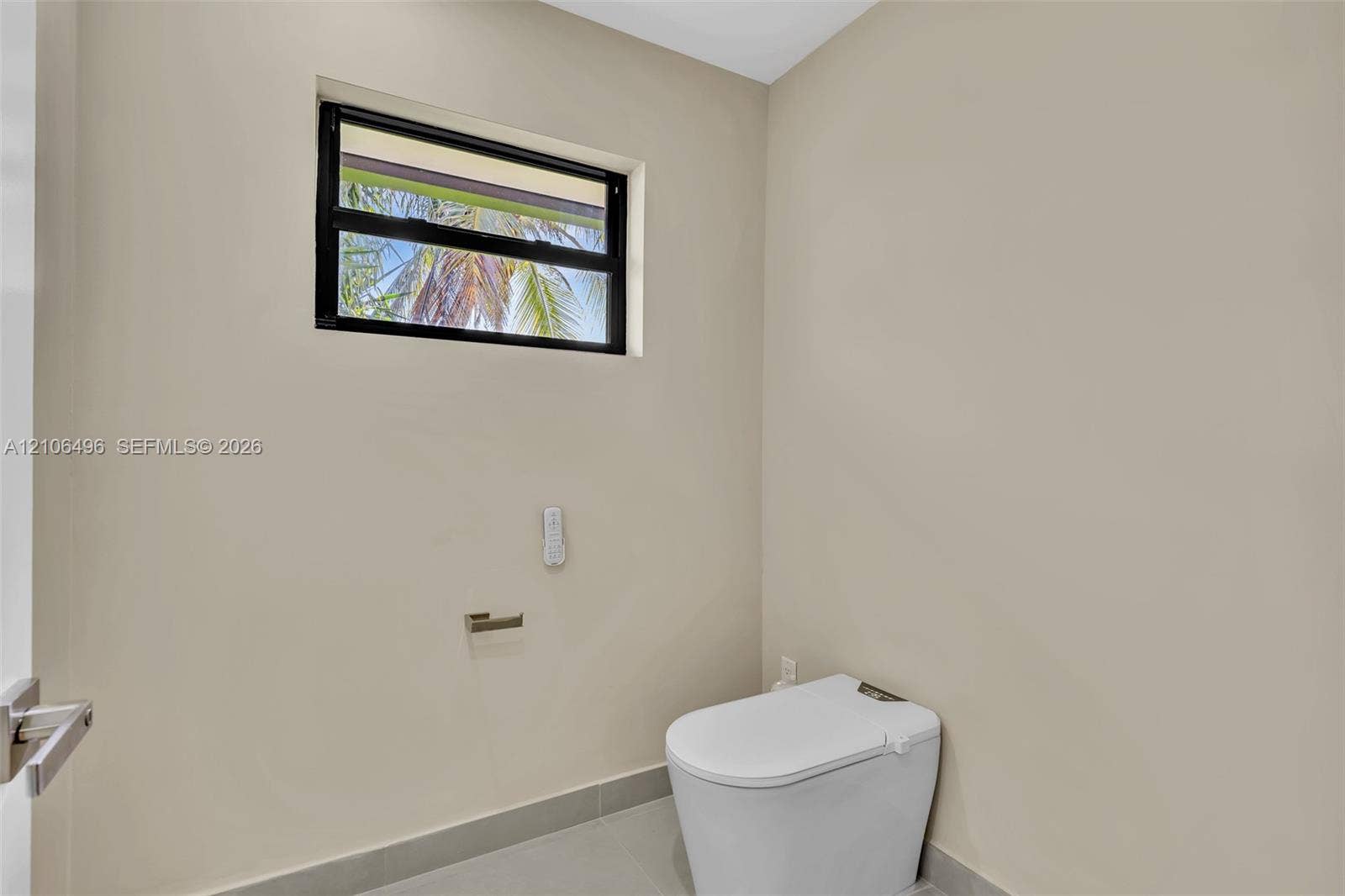 High-profile window with black frame, wall-mounted toilet, and sleek metal toilet paper holder