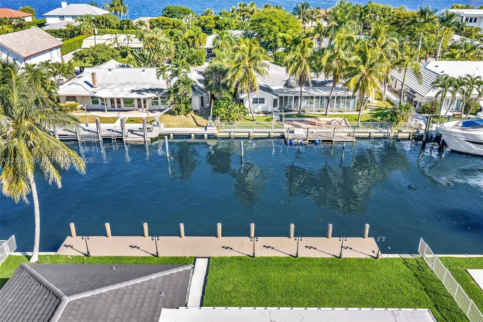 Waterfront property featuring a private boat dock, bulkheaded seawall, and manicured lawn