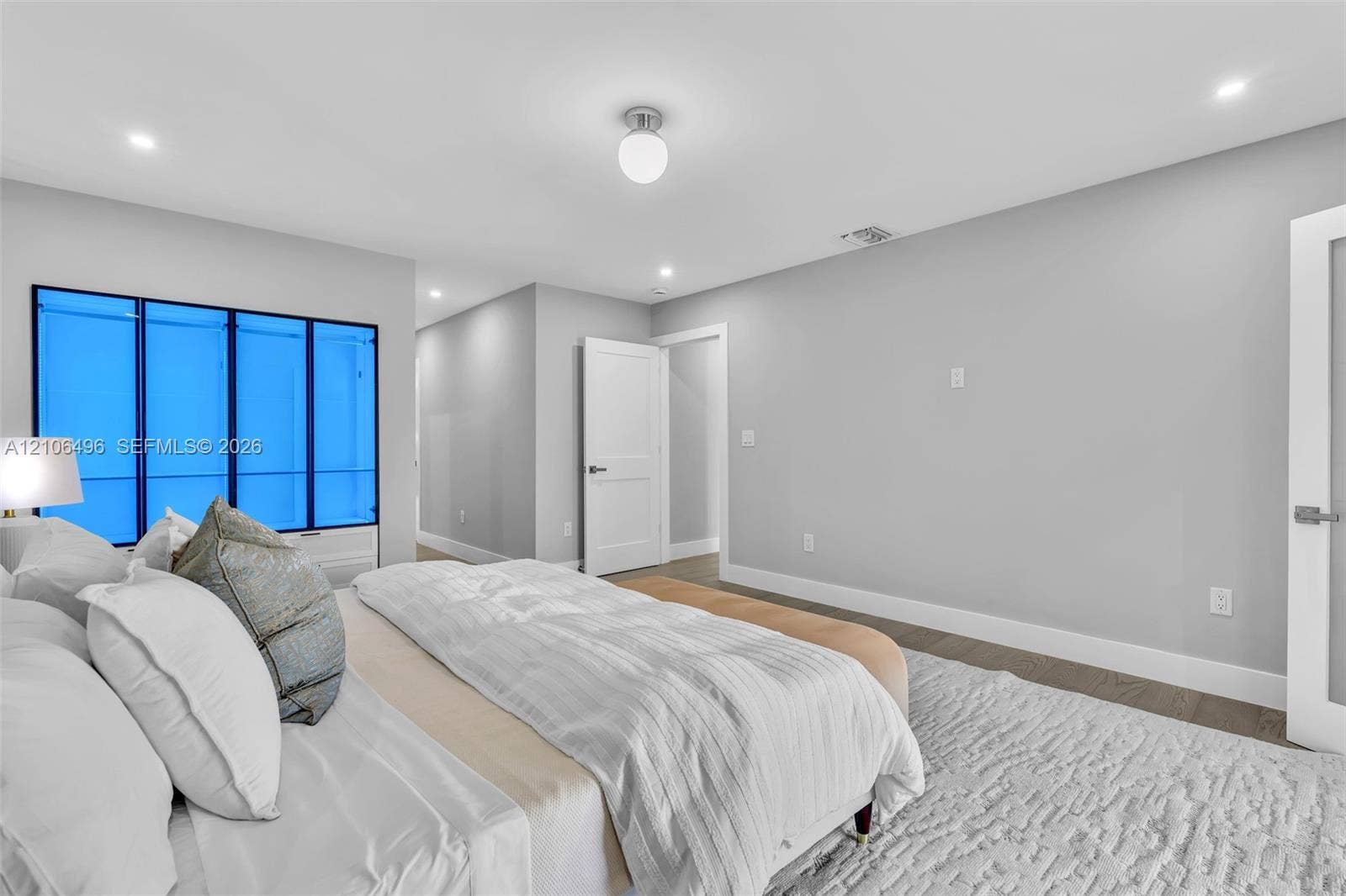 Interior space featuring wood-finish flooring, neutral wall paint, recessed lighting, and a multi-panel window with a dark frame