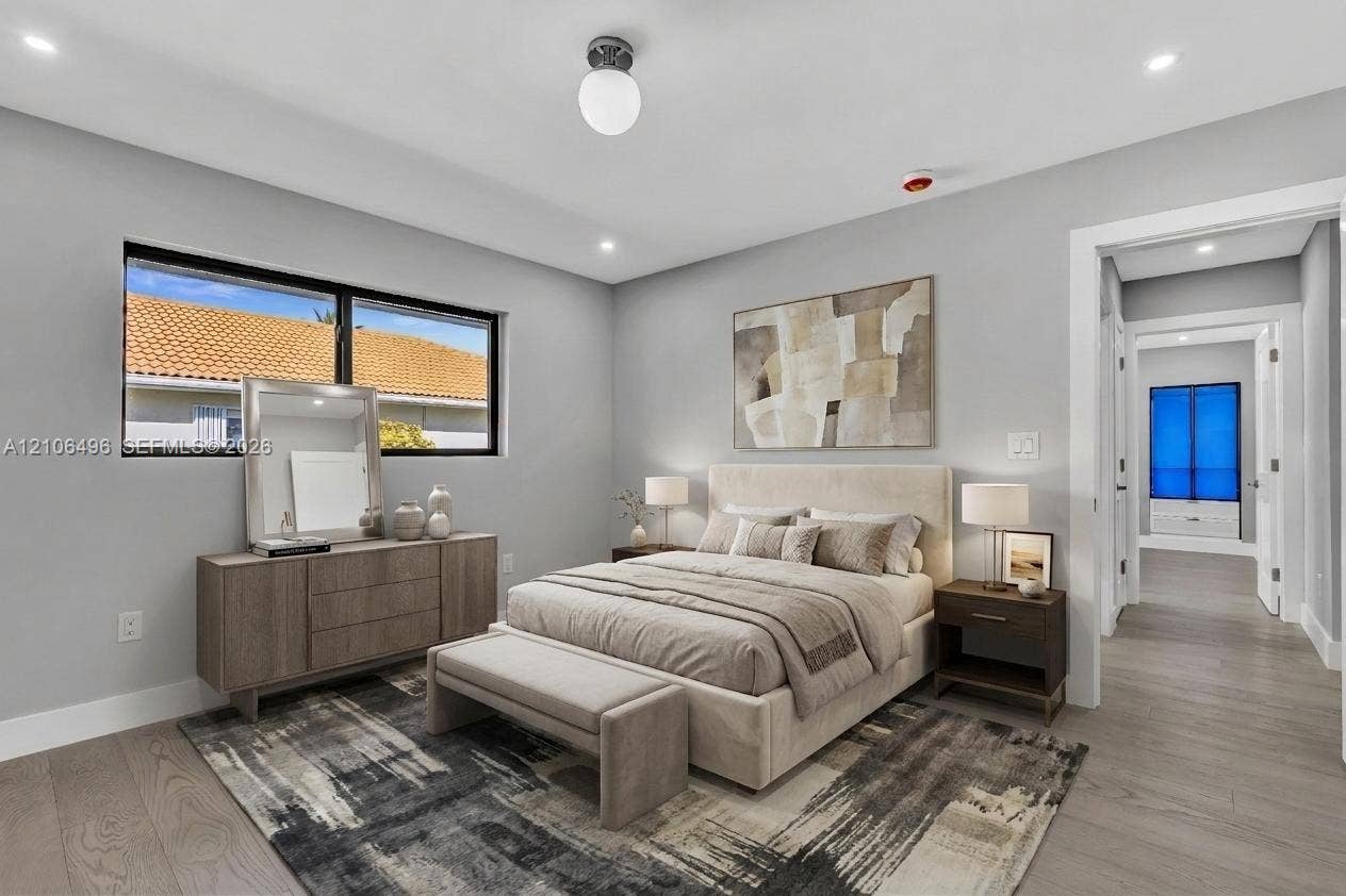 Neutral-toned interior featuring wood-finish flooring, recessed lighting, a modern globe-style ceiling fixture, and a large window with black frames