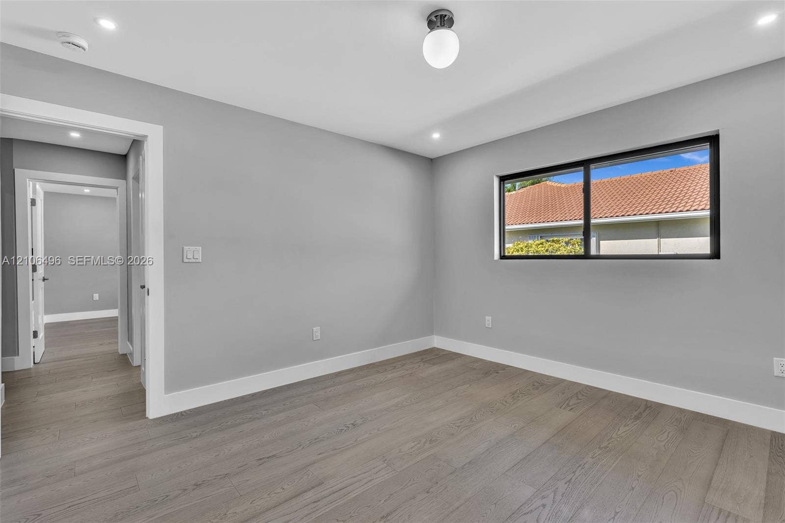 Interior space featuring wood-finish flooring, neutral wall paint, recessed lighting, a globe-style light fixture, and a black-framed window