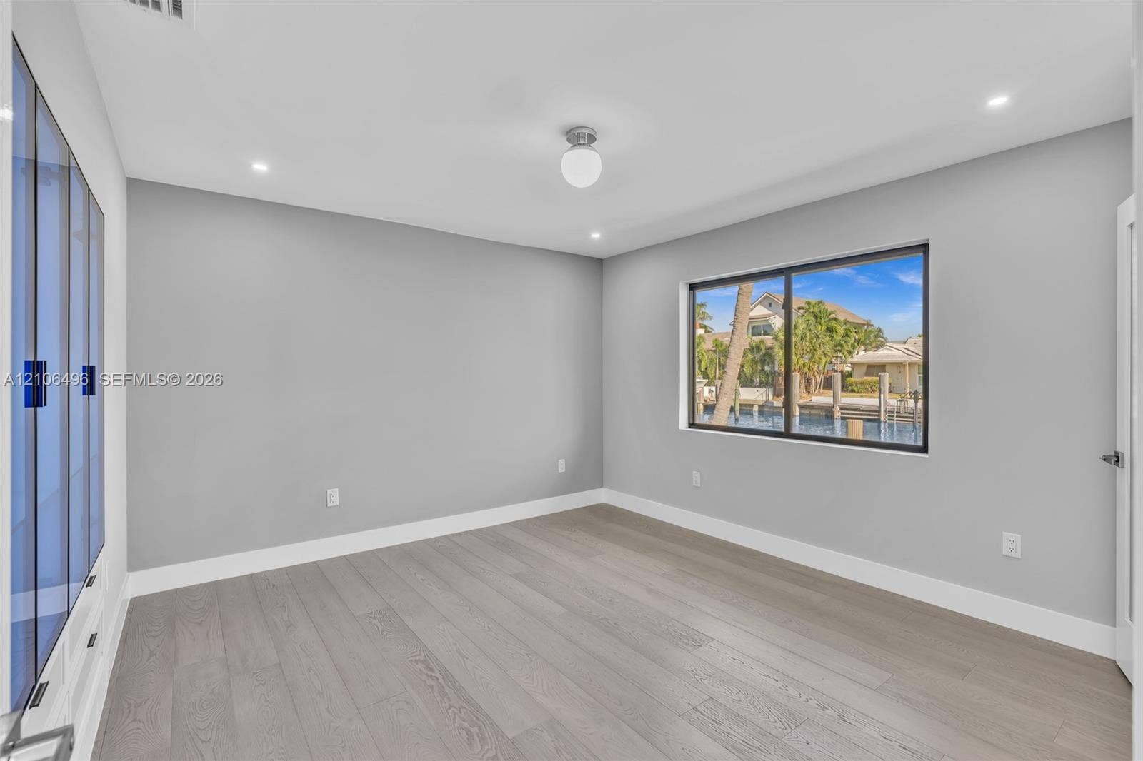 Interior space featuring wood-finish flooring, built-in floor-to-ceiling cabinetry, recessed lighting, and a window with water access exposure
