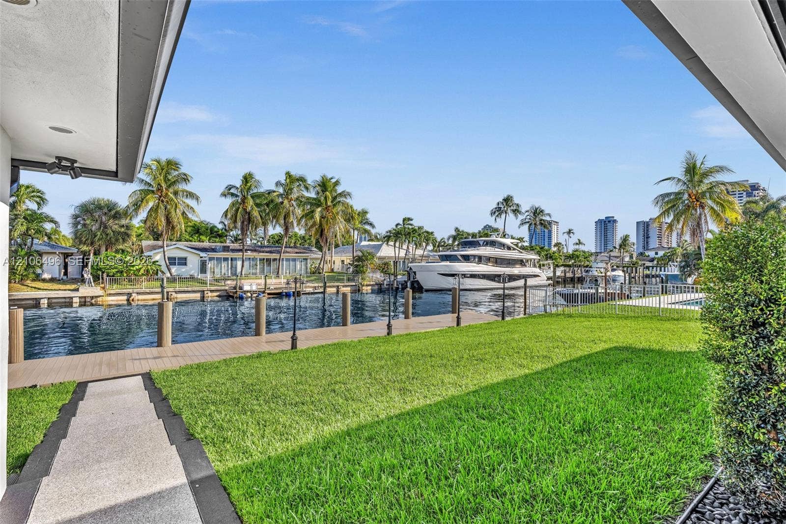 Waterfront grounds featuring a private dock, bulkhead, expansive lawn, and concrete pathway