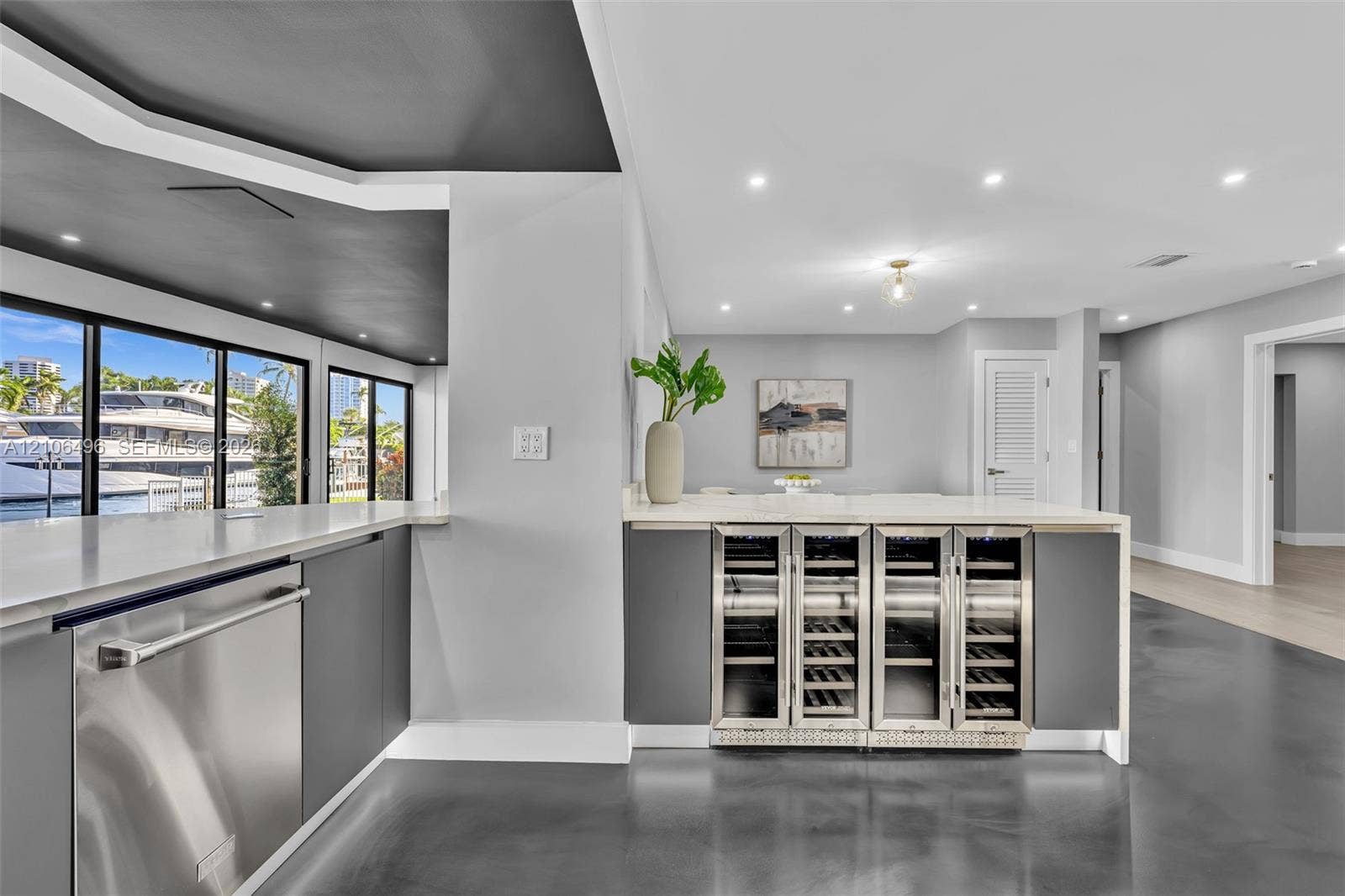 Wet bar featuring integrated stainless steel under-counter wine refrigerators, solid-surface countertops, recessed lighting, and large-format floor tiling