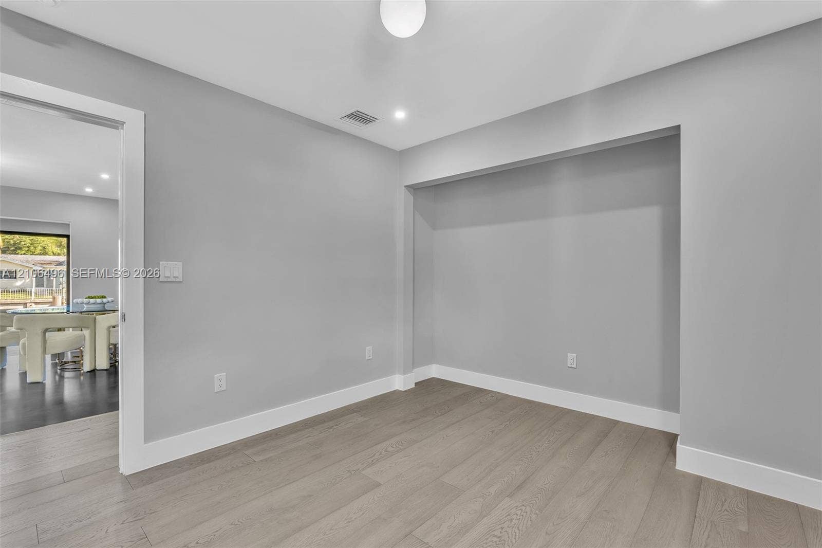Neutral-toned interior featuring wood-finish flooring, recessed wall niche, and flush-mount lighting fixture