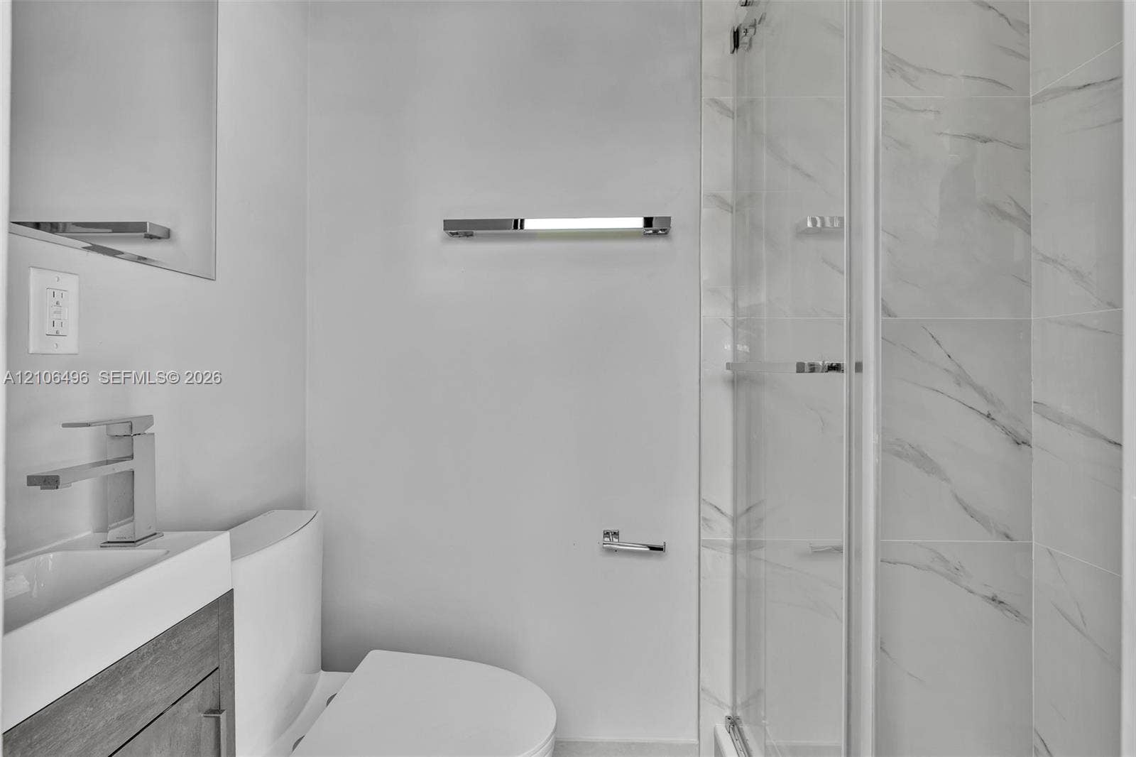 Modern bathroom featuring a wood-finish vanity, rectangular vessel sink with a polished chrome faucet, glass-enclosed shower with tiled walls, and polished chrome hardware