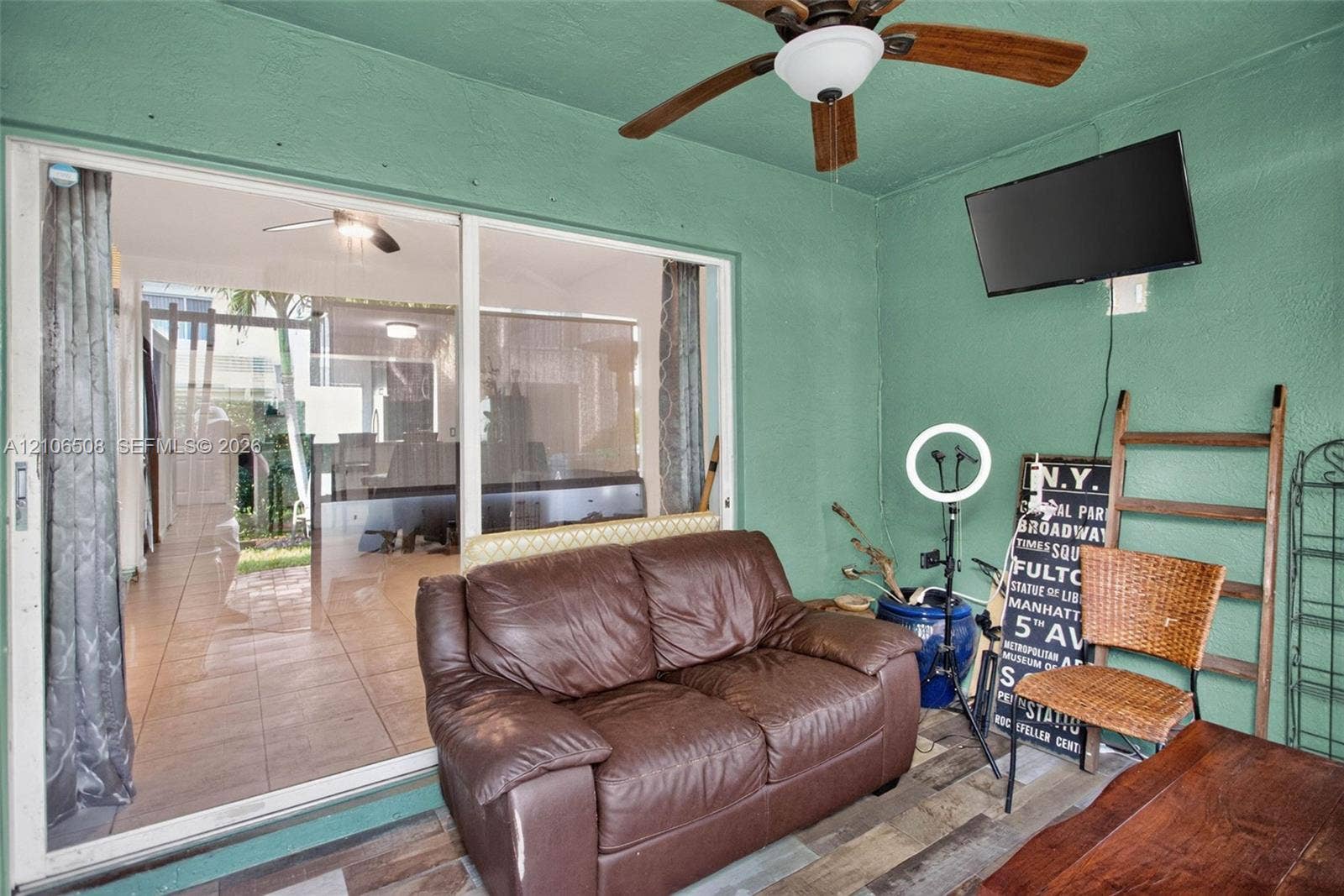 Enclosed patio featuring wood-finish flooring, a ceiling fan with light fixture, and large sliding glass doors