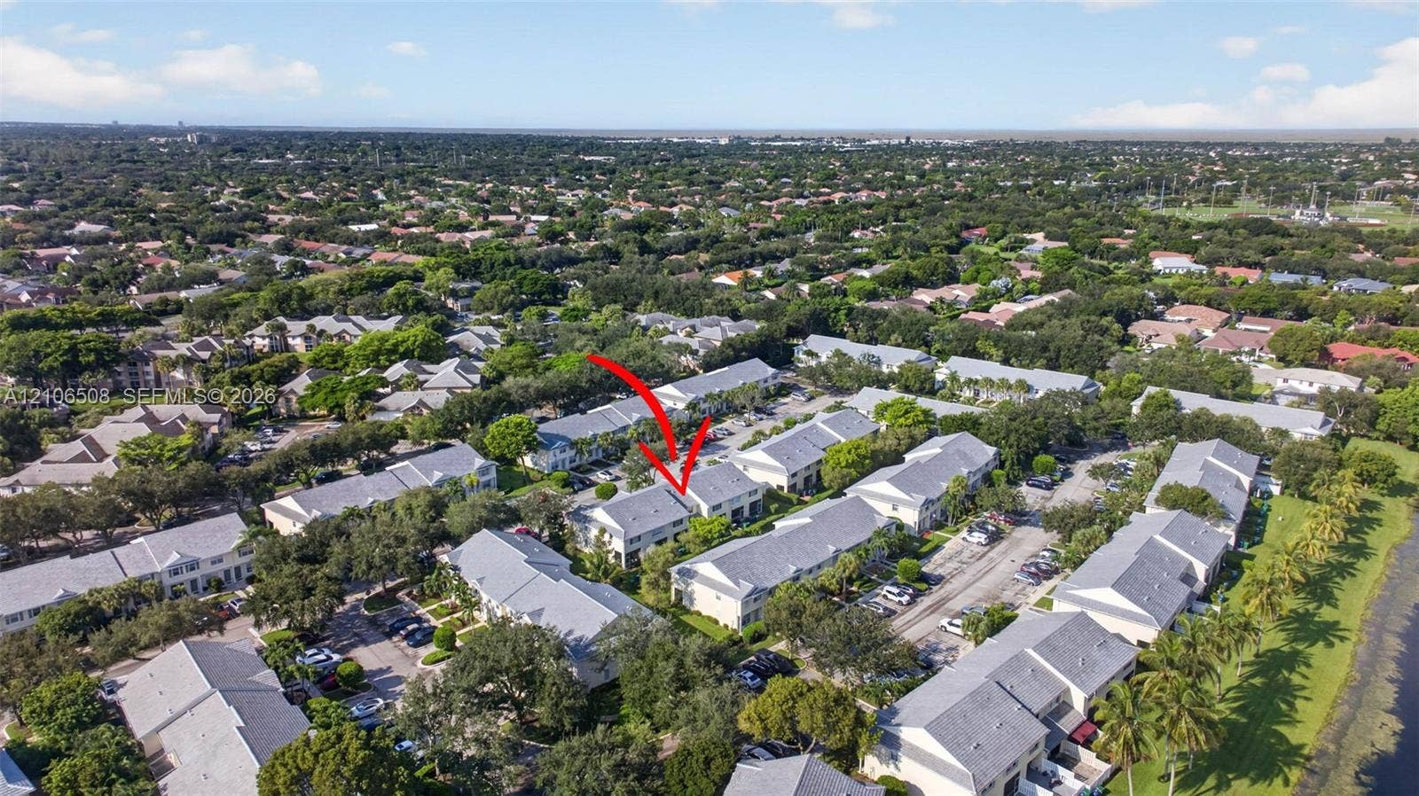 Aerial perspective of multi-family residential structure featuring a neutral-toned exterior, gabled rooflines, and mature canopy trees