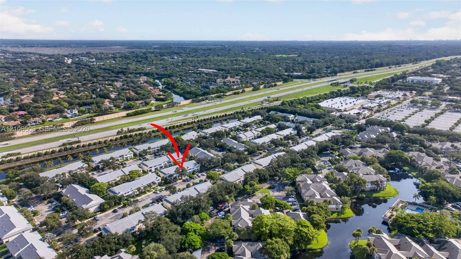 Aerial perspective featuring a multi-unit residential complex characterized by light-toned rooflines and extensive mature landscaping