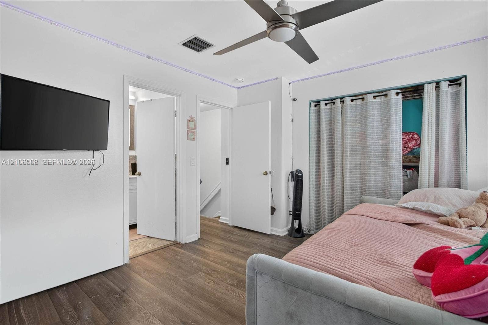 Wood-finish flooring, brushed metal ceiling fan with integrated lighting, and multiple interior passage doors