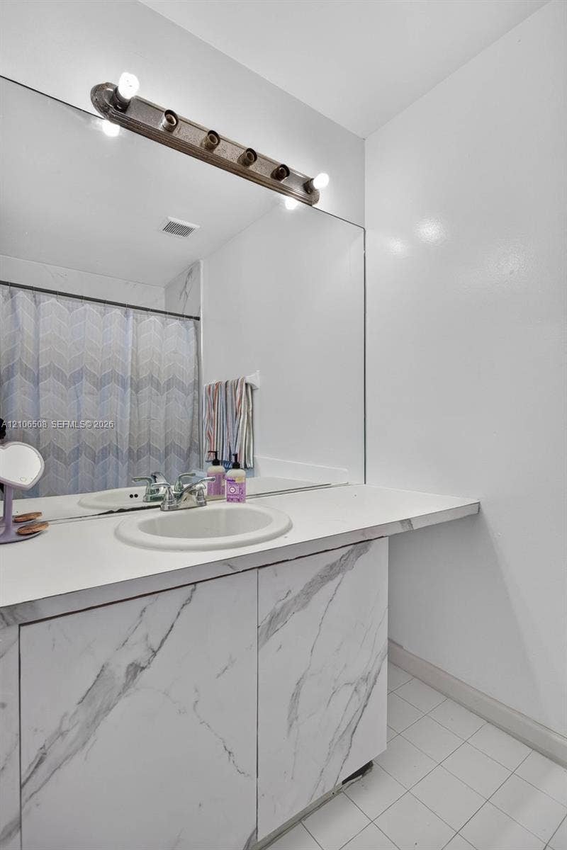 Vanity with a solid surface countertop, integrated oval sink, and stone-finish cabinetry