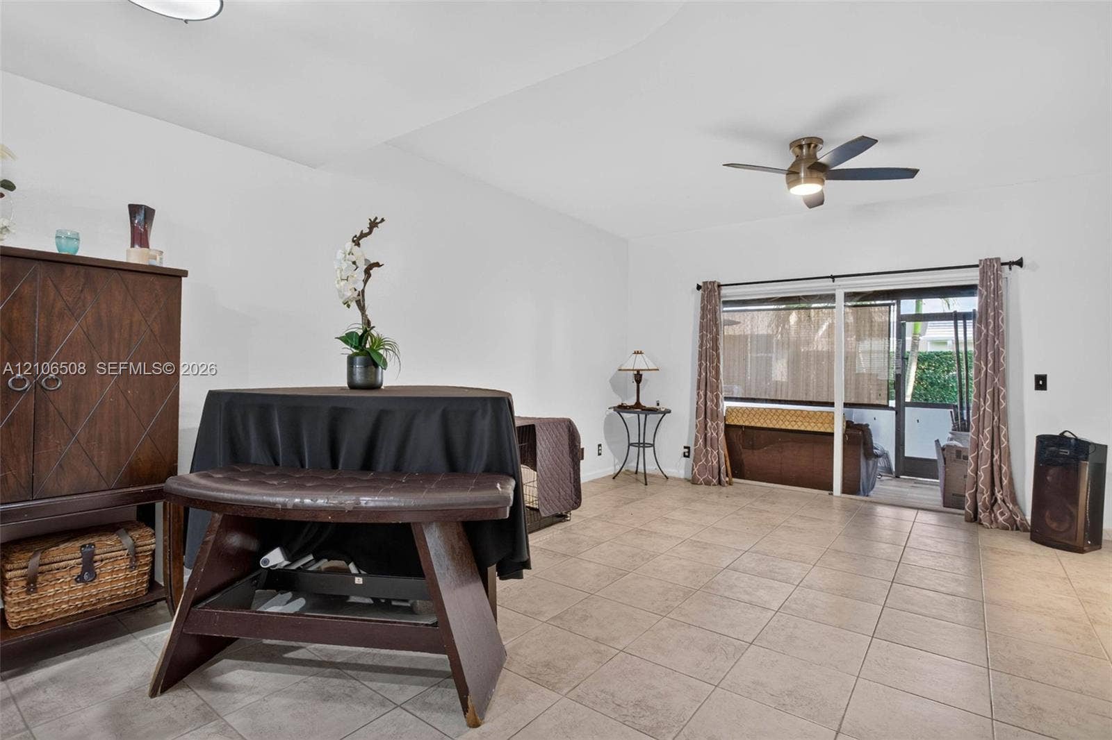 Open living area featuring large-format ceramic tile flooring, a ceiling fan with integrated lighting, and sliding glass doors with access to an exterior screened enclosure