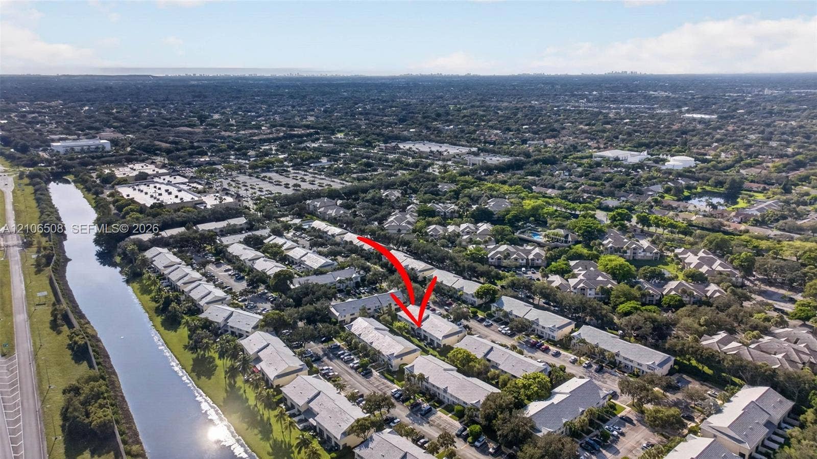 Aerial perspective of a multi-unit residential property featuring a pitched roofline, surface parking, and manicured landscaping