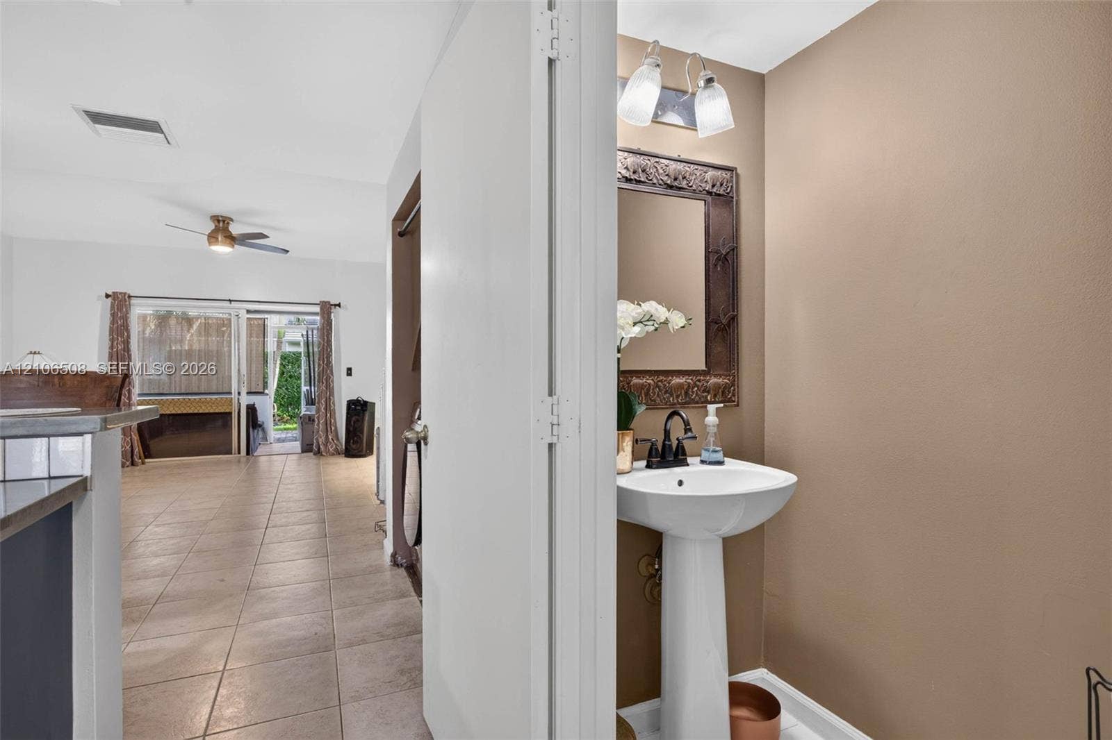 Powder room featuring a pedestal sink, arched vanity mirror, matte black faucet, and two-light wall-mounted fixture