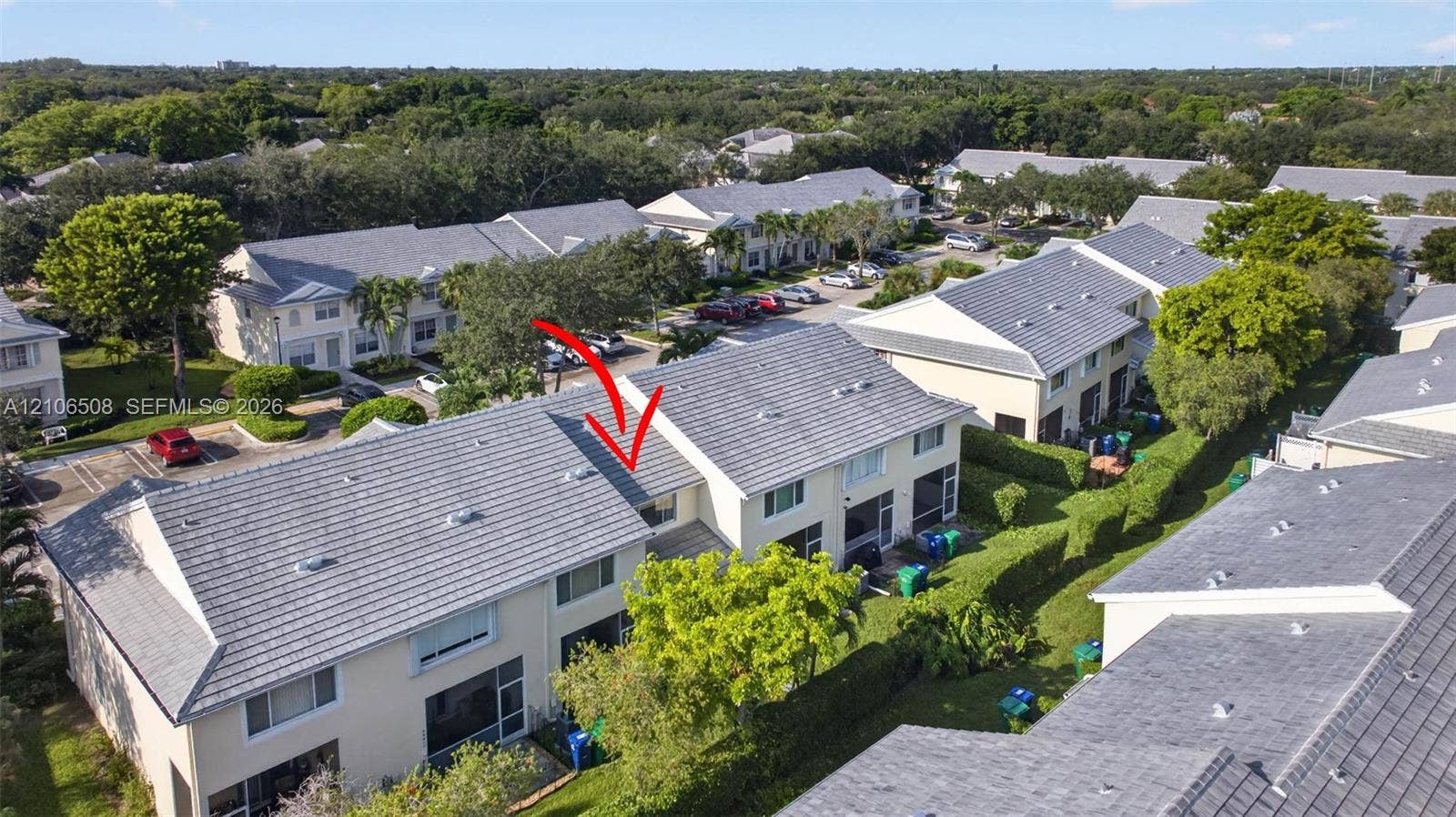 Two-story townhouse featuring a concrete tile roof, light-colored stucco exterior, and ground-level patio