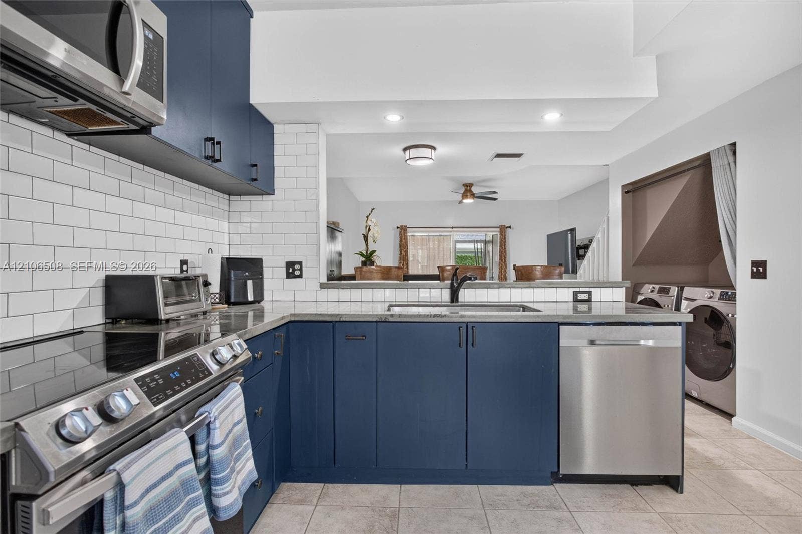 Kitchen featuring deep blue cabinetry, white subway tile backsplash, stainless steel appliances, stone-finish countertops, and recessed lighting