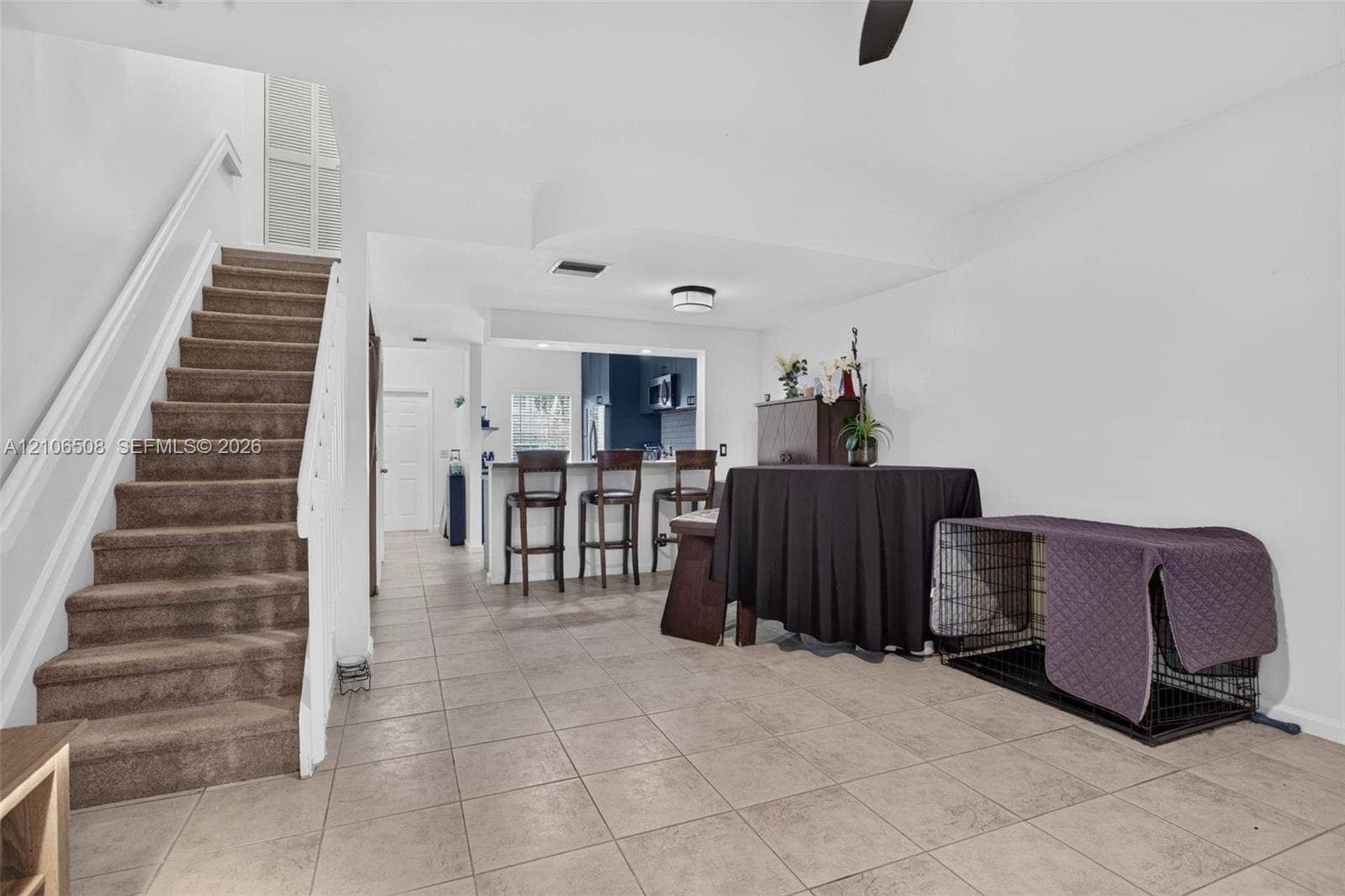 Open floor plan featuring tile flooring, a staircase with a white handrail, and a kitchen breakfast bar