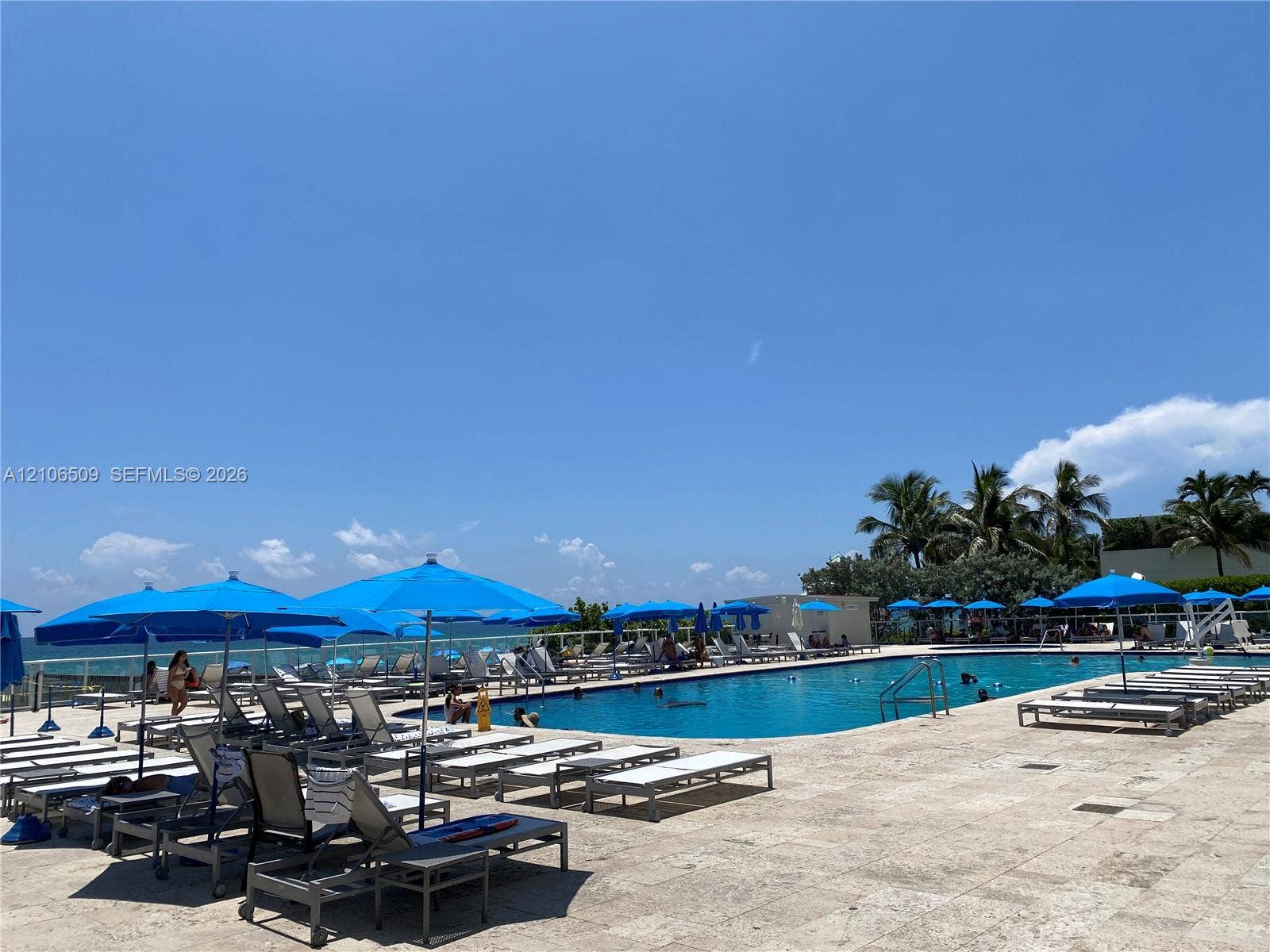 Outdoor swimming pool with stone-tiled decking, metal pool fencing, and perimeter landscaping