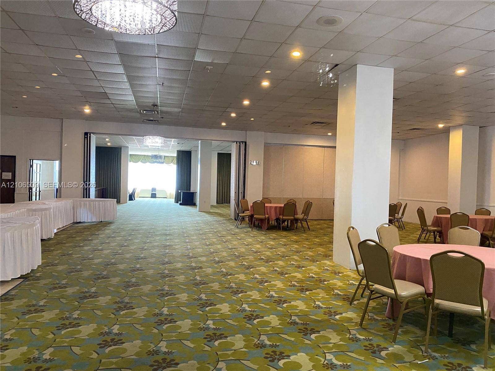 Expansive interior space featuring a drop ceiling with recessed lighting, structural support columns, and decorative pendant fixtures