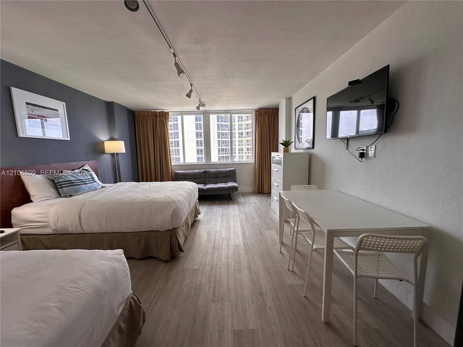 Wood-finish flooring, accent wall, multi-pane windows, and track lighting