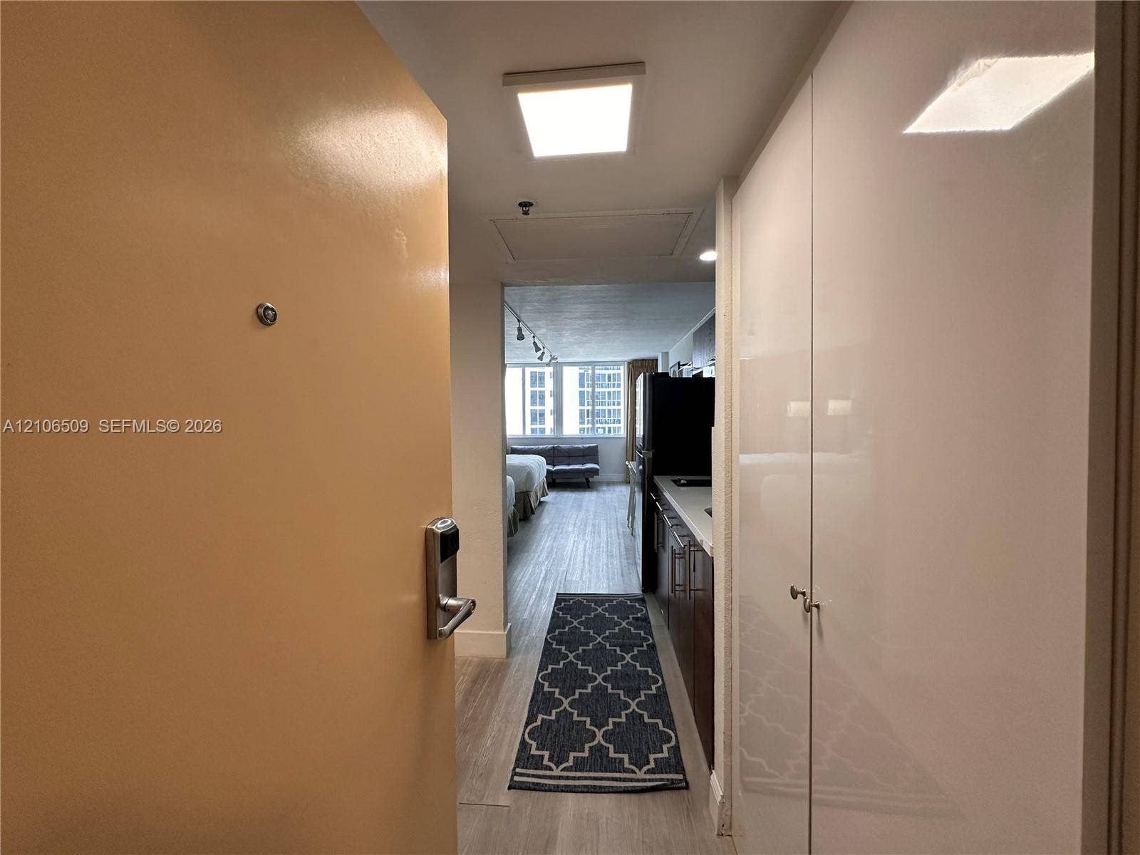Entryway featuring high-gloss white built-in cabinetry, wood-finish flooring, and recessed LED ceiling lighting