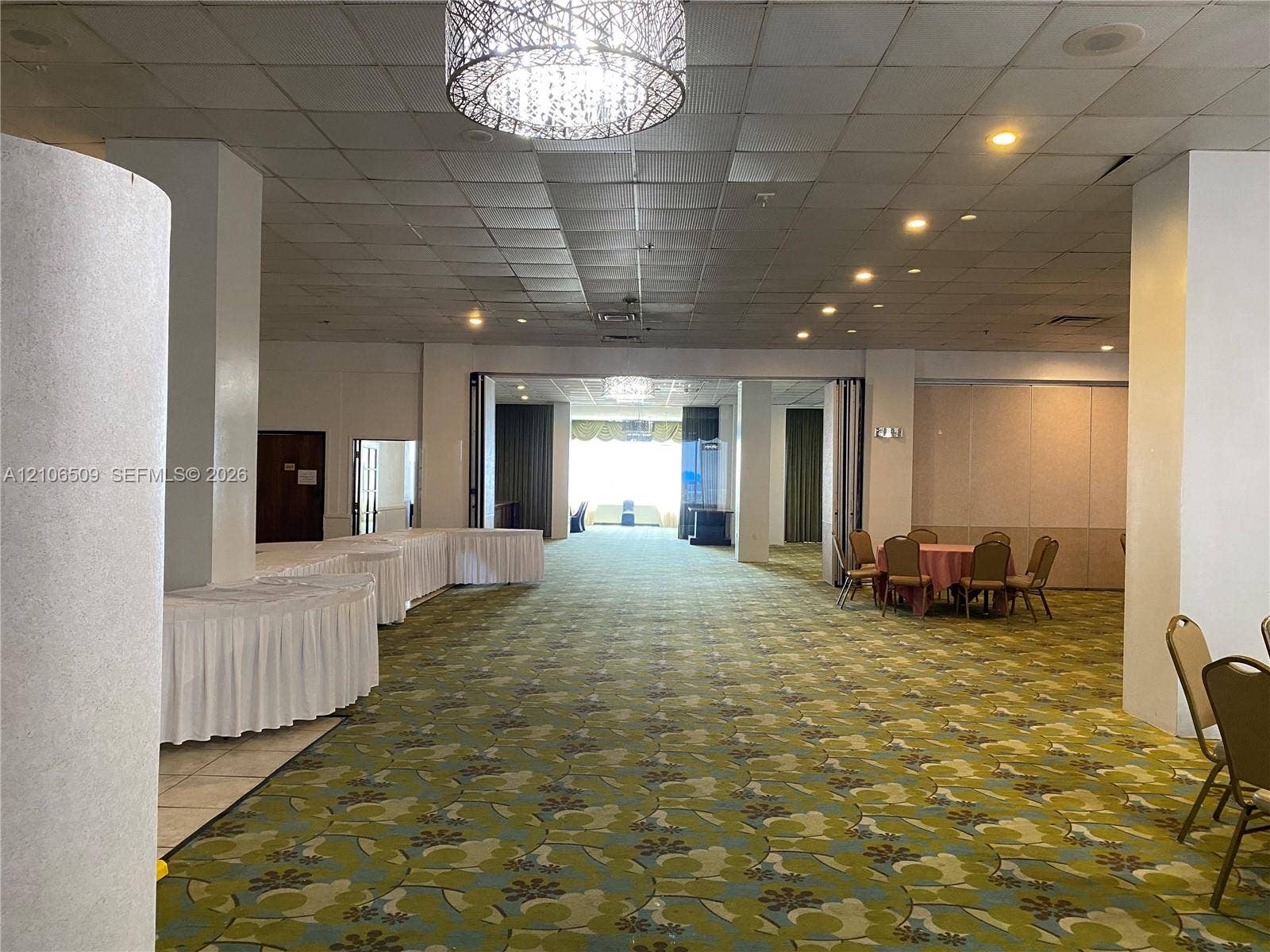Expansive open-concept interior featuring a drop ceiling, decorative drum pendant lighting, recessed lighting, and folding accordion partition walls
