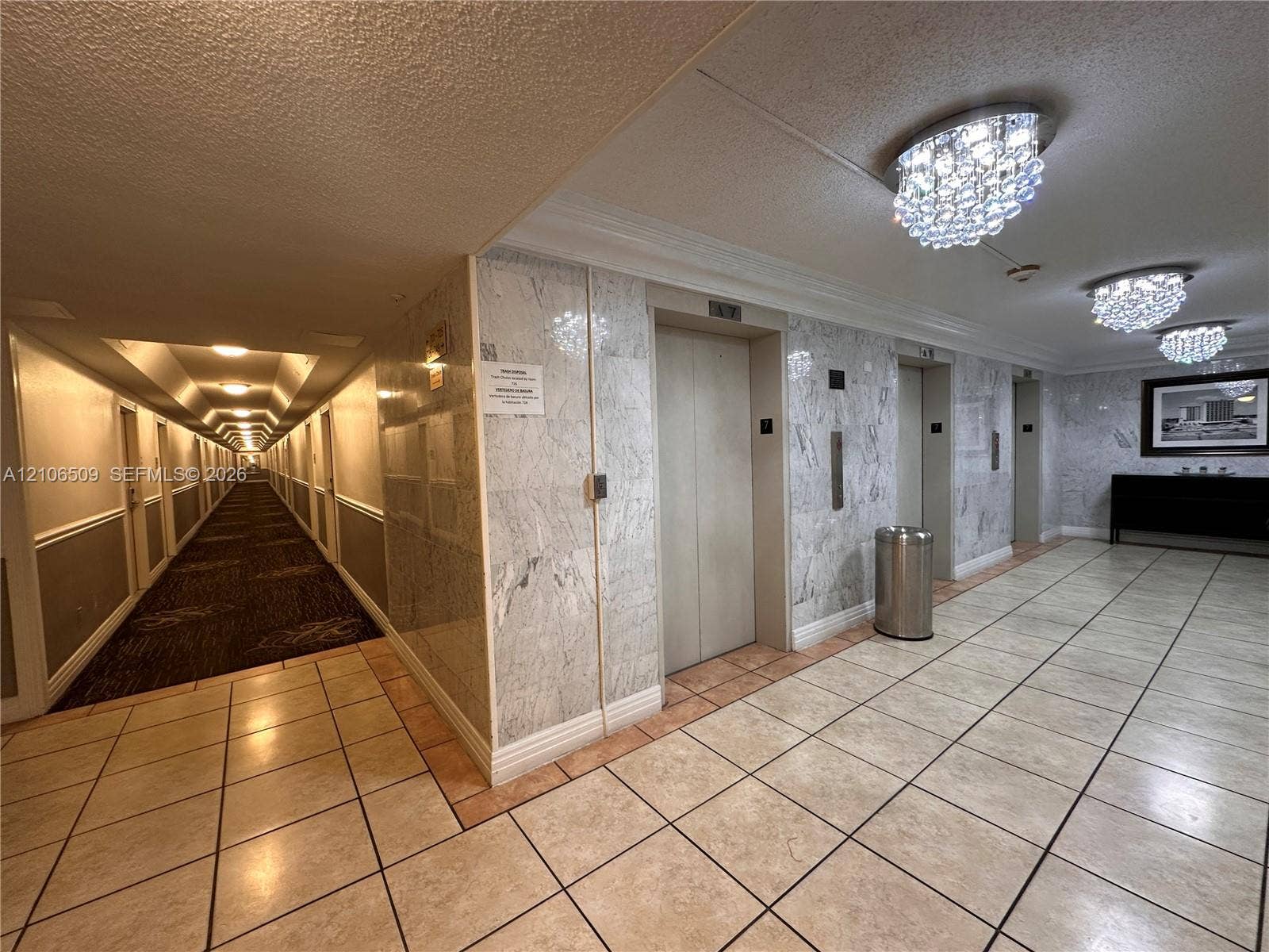 Elevator lobby featuring stone wall paneling, tile flooring, and crystal-style flush mount ceiling lighting