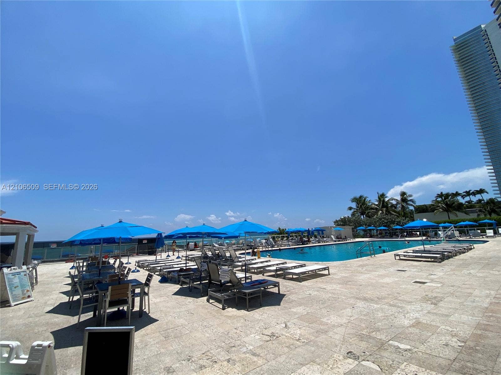 Outdoor swimming pool featuring stone deck tiling and ocean horizon backdrop