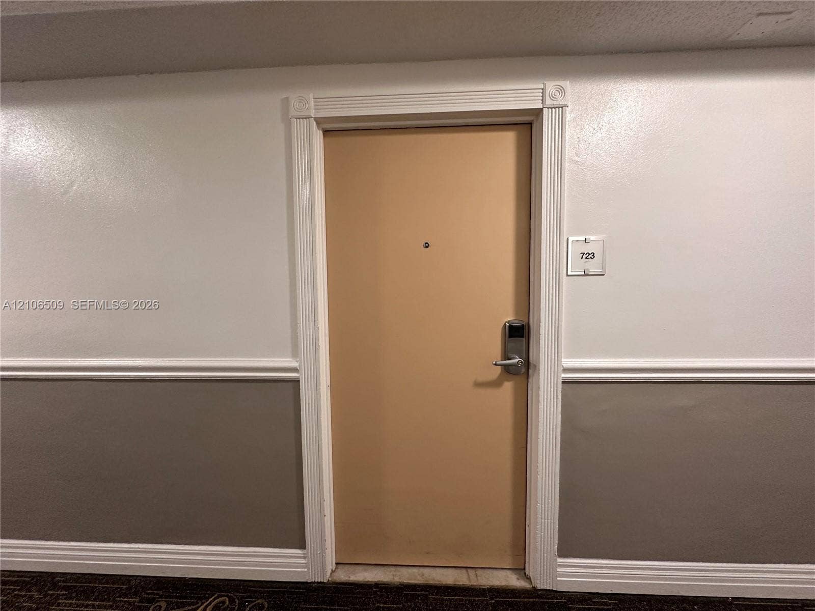 Entryway featuring a solid door with a metal electronic lock, decorative fluted casing, and a peephole, complemented by chair rail molding