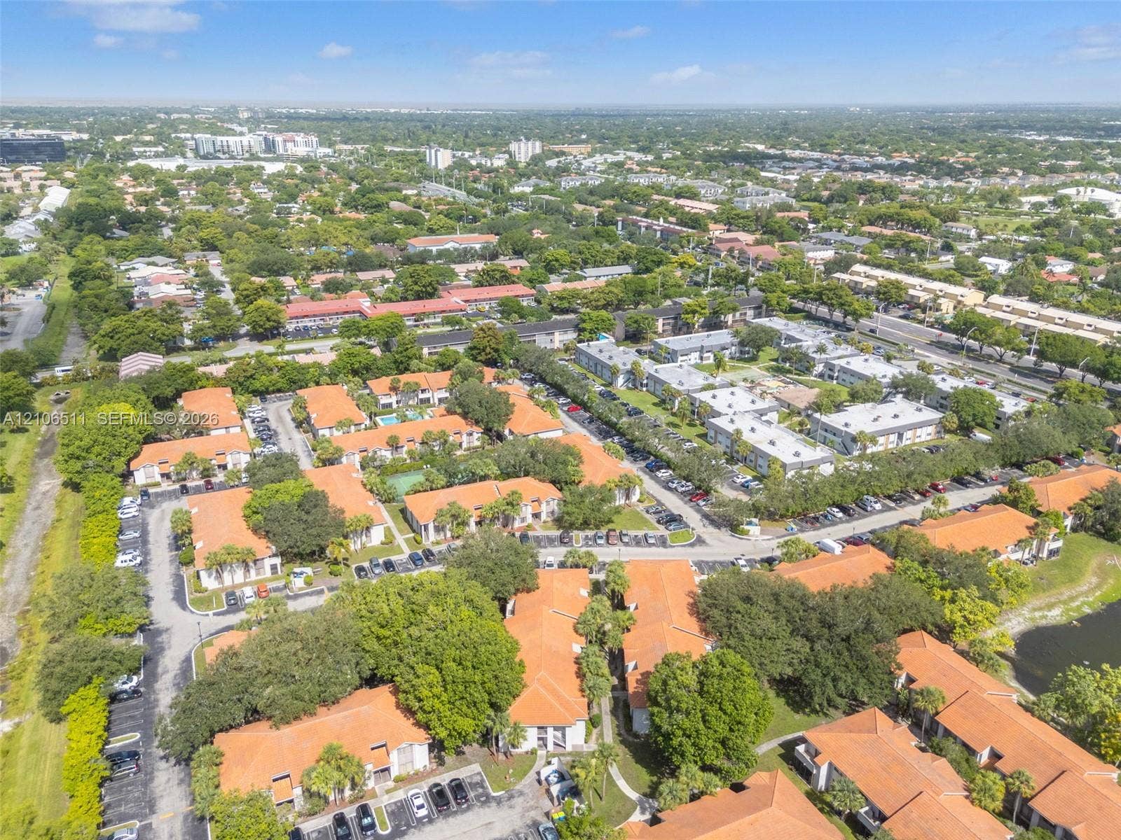 3229 Coral Lake Drive, #3229, Coral Springs, FL 33065 Aerial view of a residential complex featuring terracotta-tiled rooflines, mature landscaping, paved surface parking, and communal outdoor recreation areas