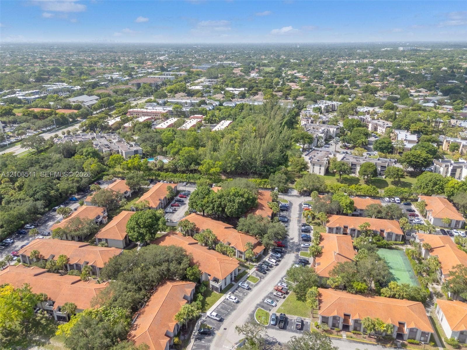 3229 Coral Lake Drive, #3229, Coral Springs, FL 33065 Aerial perspective of a multi-unit complex featuring terra-cotta tile roofing, mature landscaping, designated paved parking areas, and a community tennis court