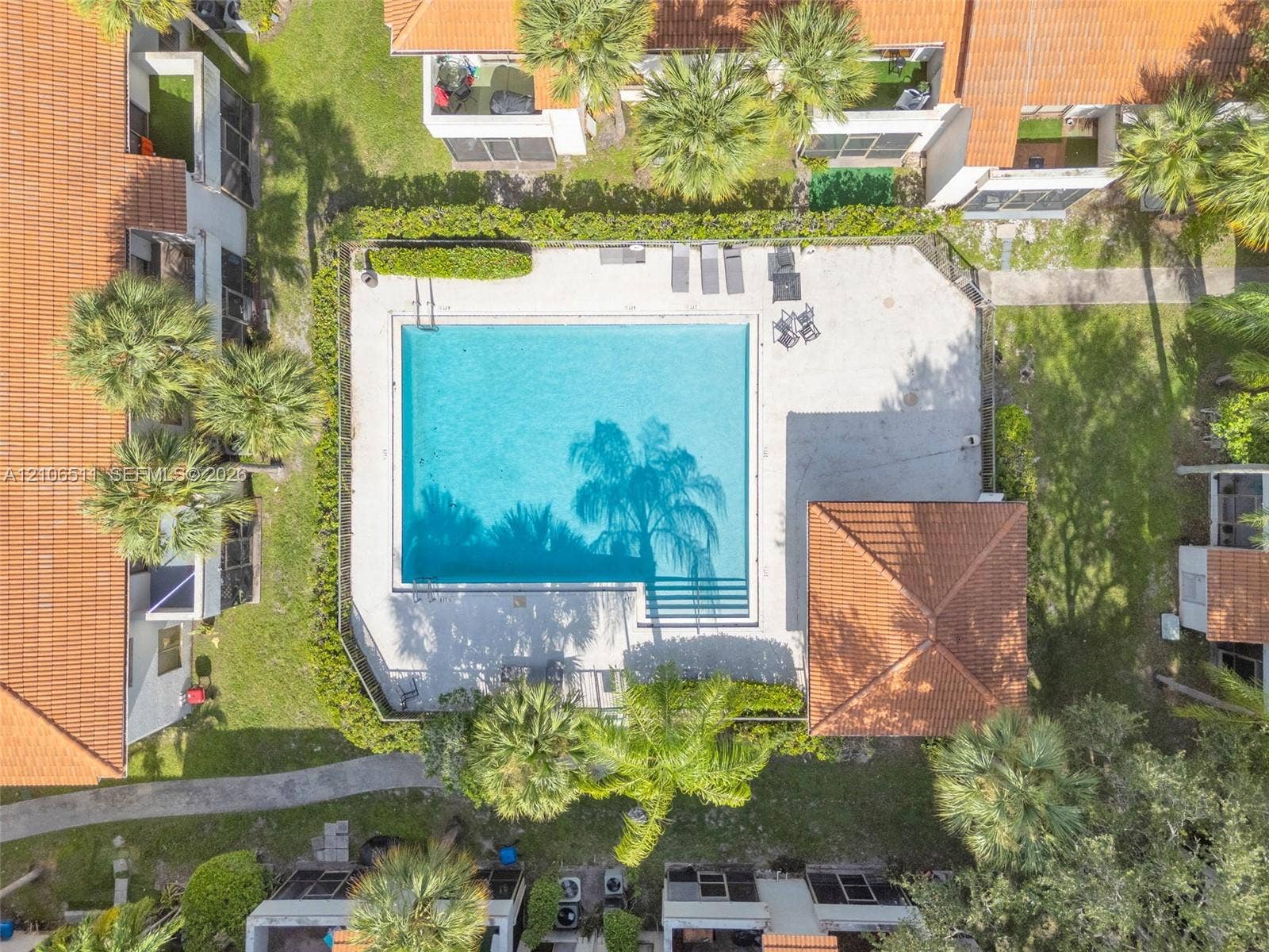 3229 Coral Lake Drive, #3229, Coral Springs, FL 33065 Community swimming pool featuring a concrete deck, integrated steps, and a covered pavilion, surrounded by manicured landscaping and mature palms